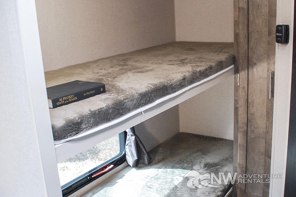 RV rental bunk beds: a top bunk with a soft mattress & book, plus a window & cabinet storage.. KZ SPREE ESCAPE 2021