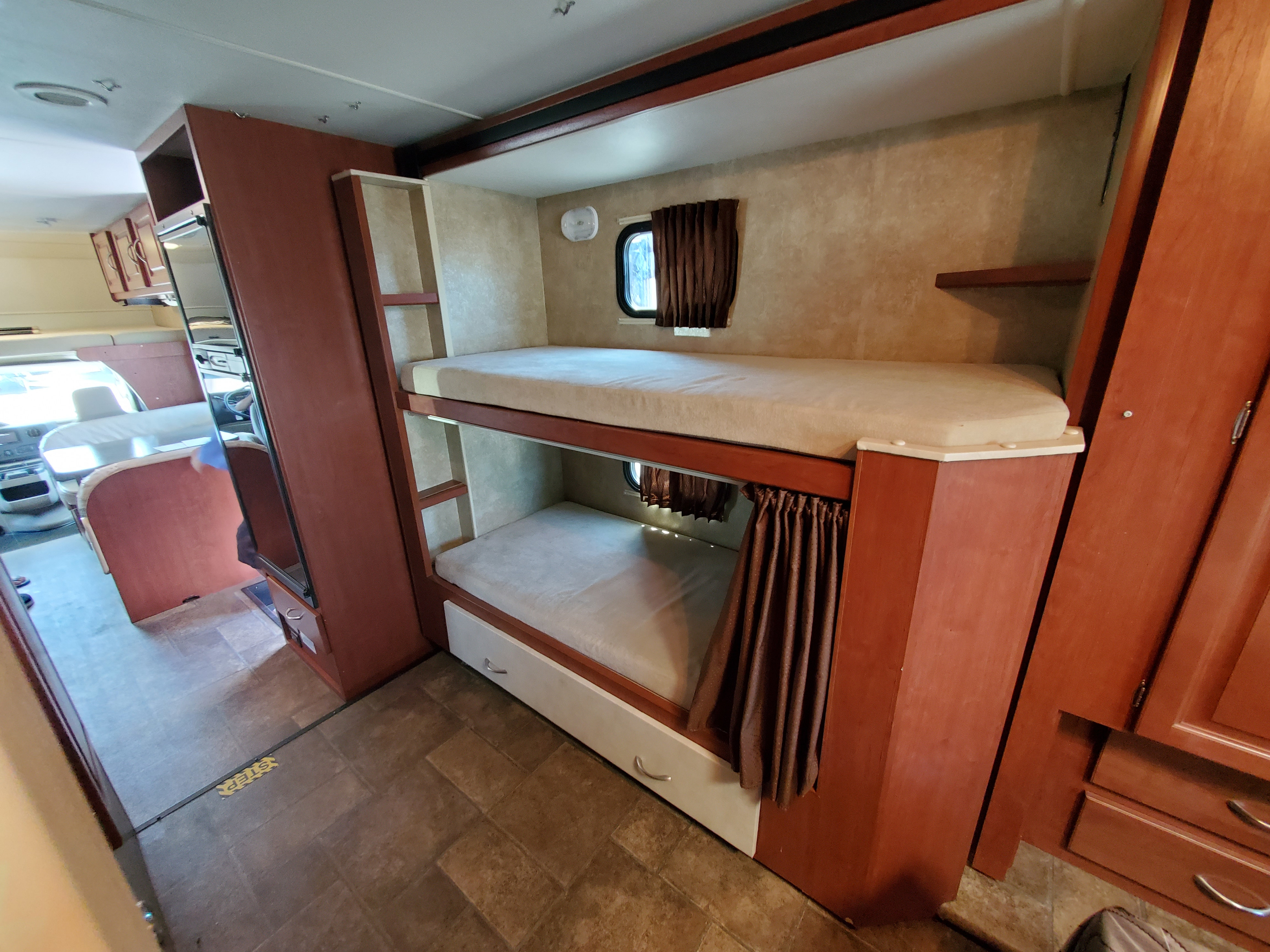 Explore this RV rental's interior, featuring comfy bunk beds, cabinet storage, and a view to the dining area.. Winnebago Minnie Winnie 2014