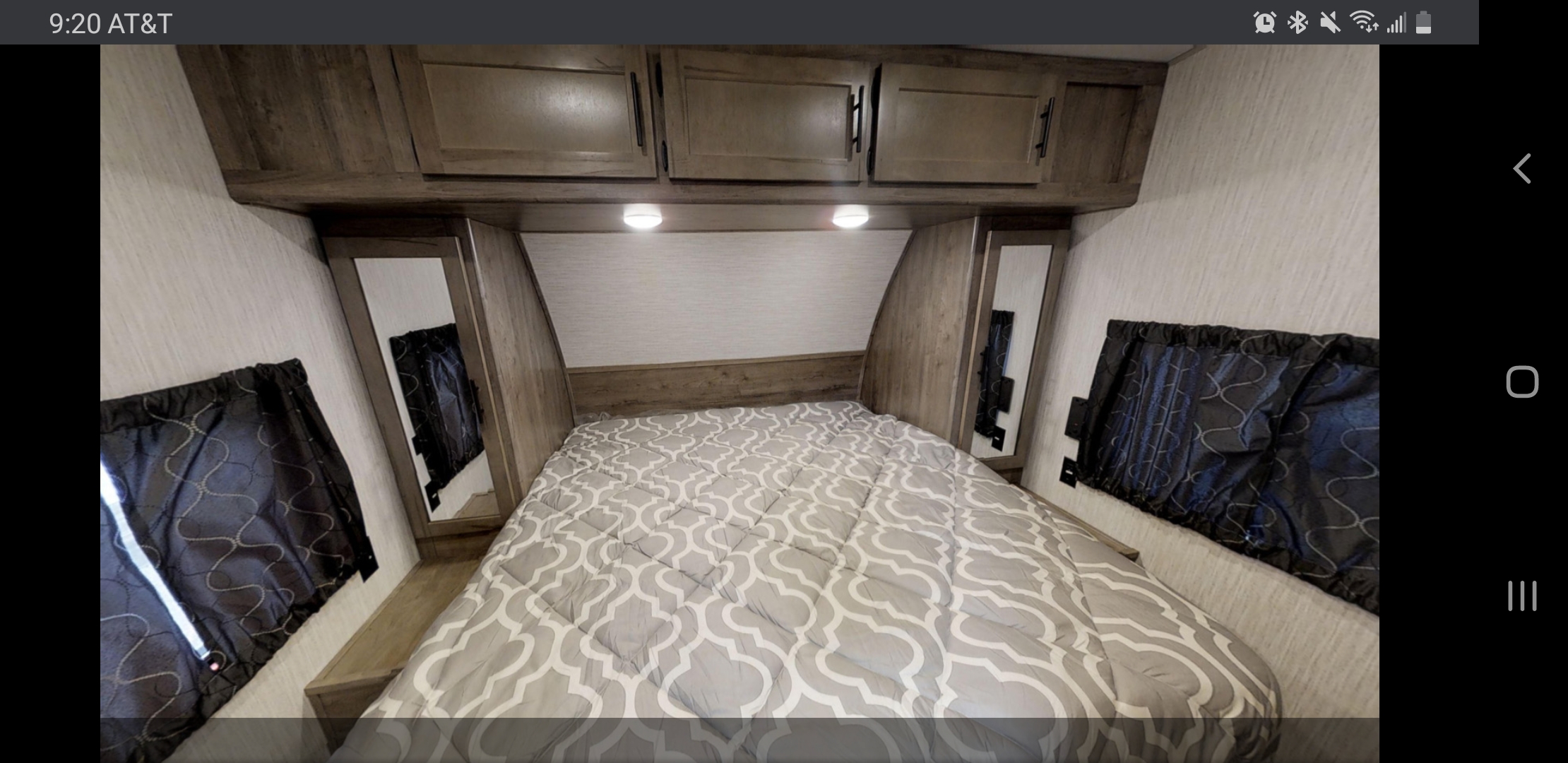 Comfortable RV rental bedroom featuring a patterned bed, overhead cabinets, and side windows.. Forest River Cherokee Wolf Pack 2021