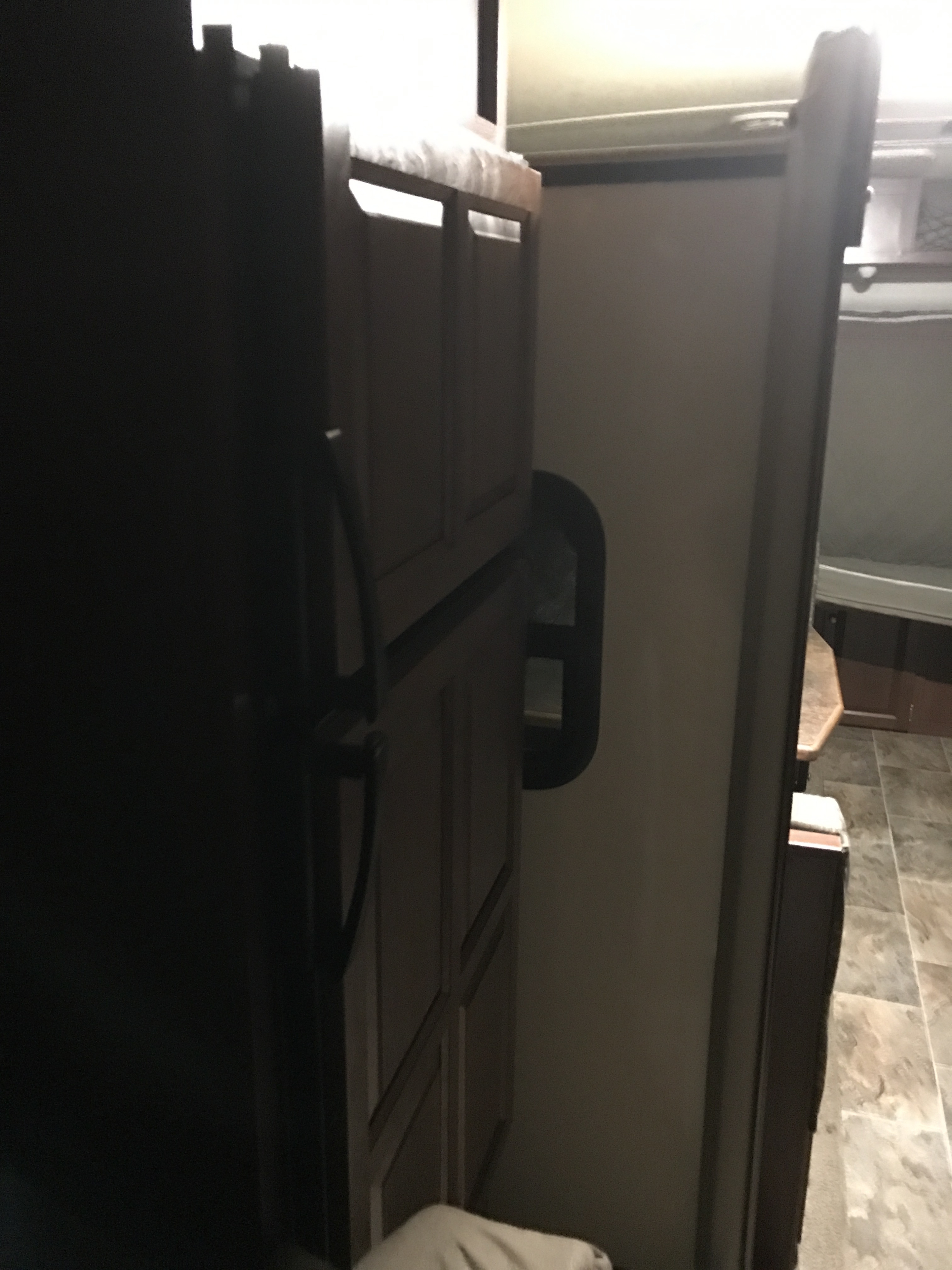 RV rental interior showcasing compact design, featuring refrigerator, cabinetry, and a glimpse of a bunk bed area with tiled flooring.. Forest River Rockwood Roo 2016