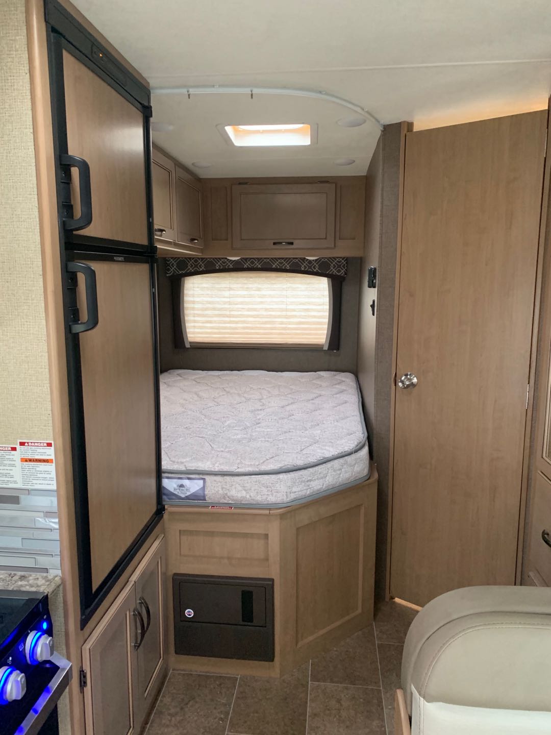 RV rental interior: cozy bed nook, compact kitchen with fridge/stove, and overhead cabinets.. Thor Chateau 2019