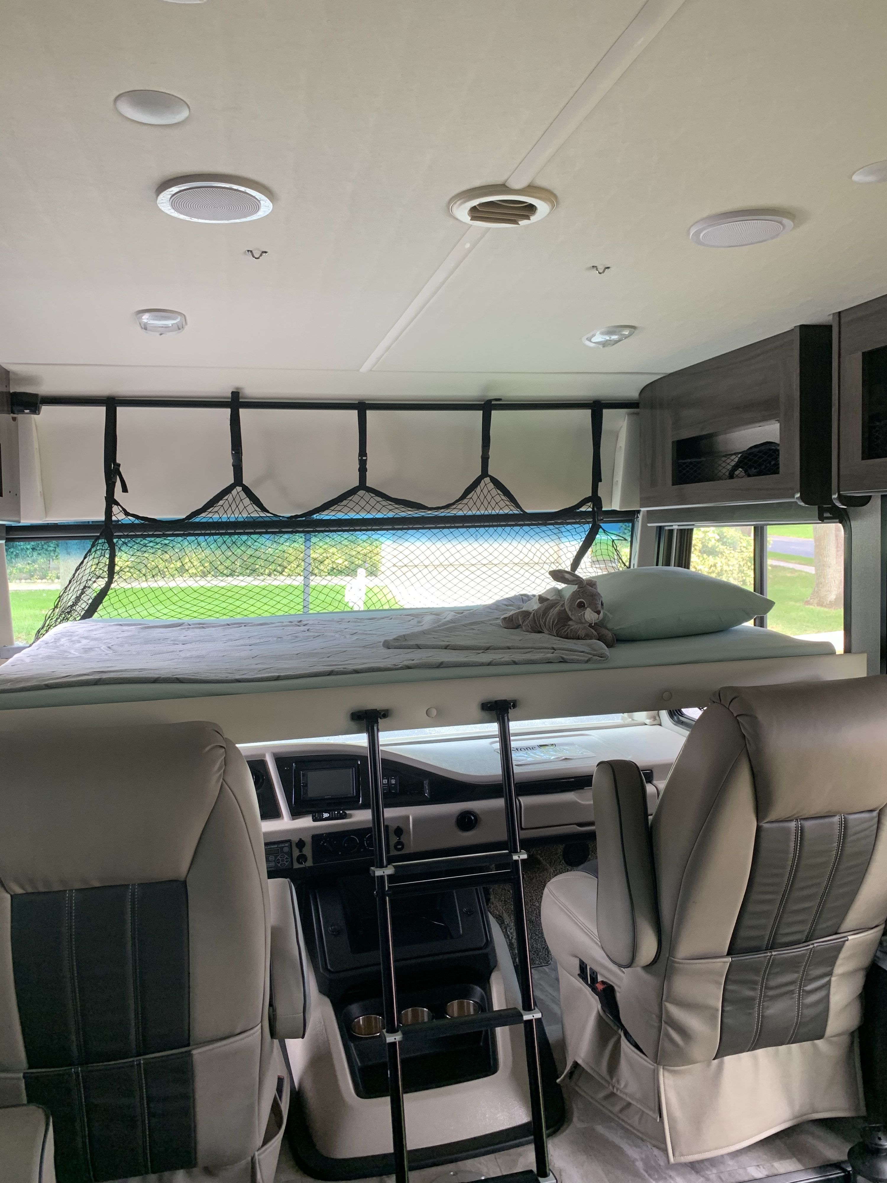 Spacious RV rental interior with a cozy cab-over bunk bed, safety net, and ladder above the front seats and dashboard.. Holiday Rambler Admiral 2021