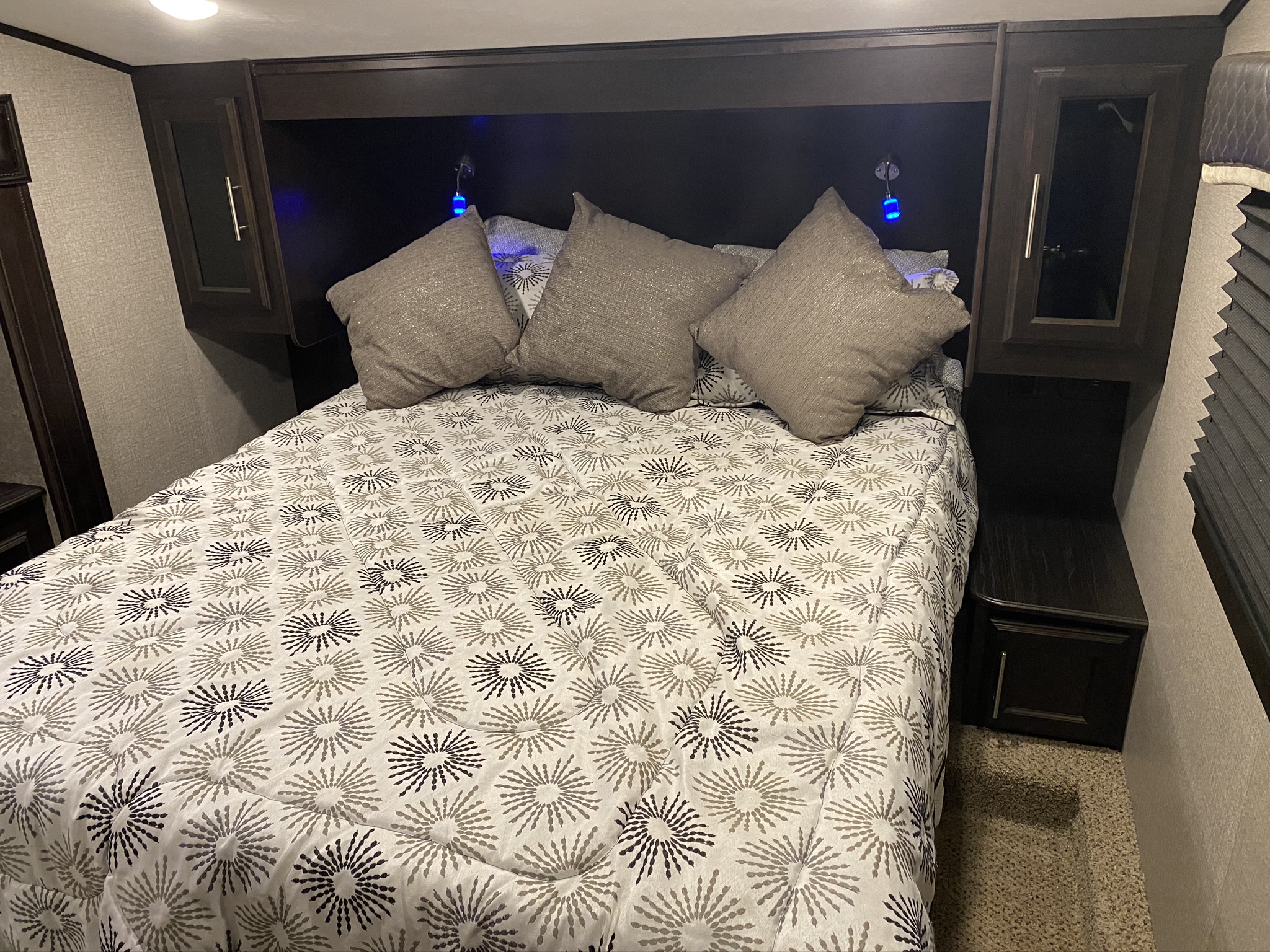 Cozy RV rental bedroom with patterned comforter, pillows, and built-in storage, ideal for compact living.. Jayco Eagle 2020