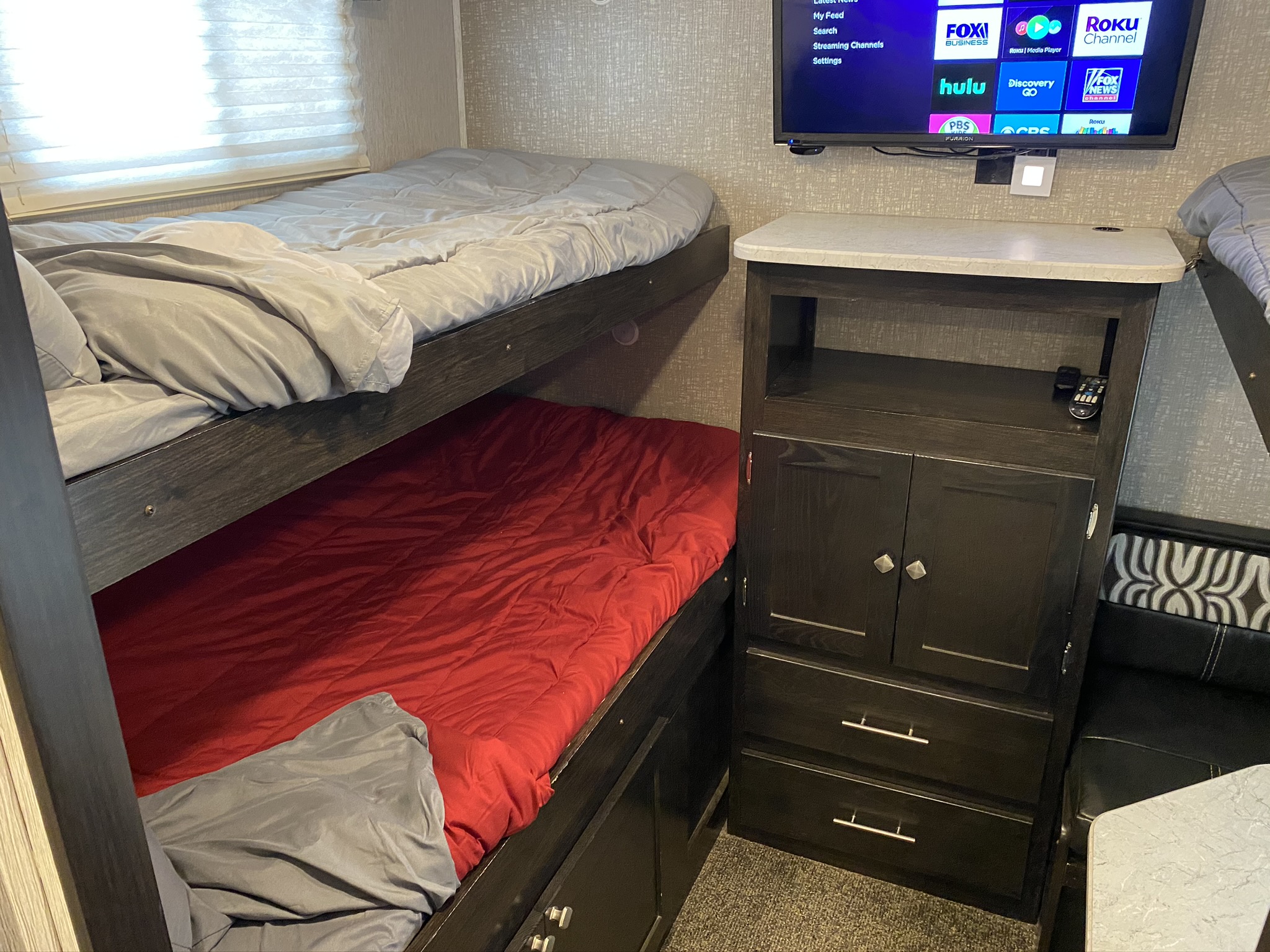 An RV rental's cozy bunk beds, complete with a mounted TV for entertainment, offering comfort in a compact space.. Heartland North Trail 2020