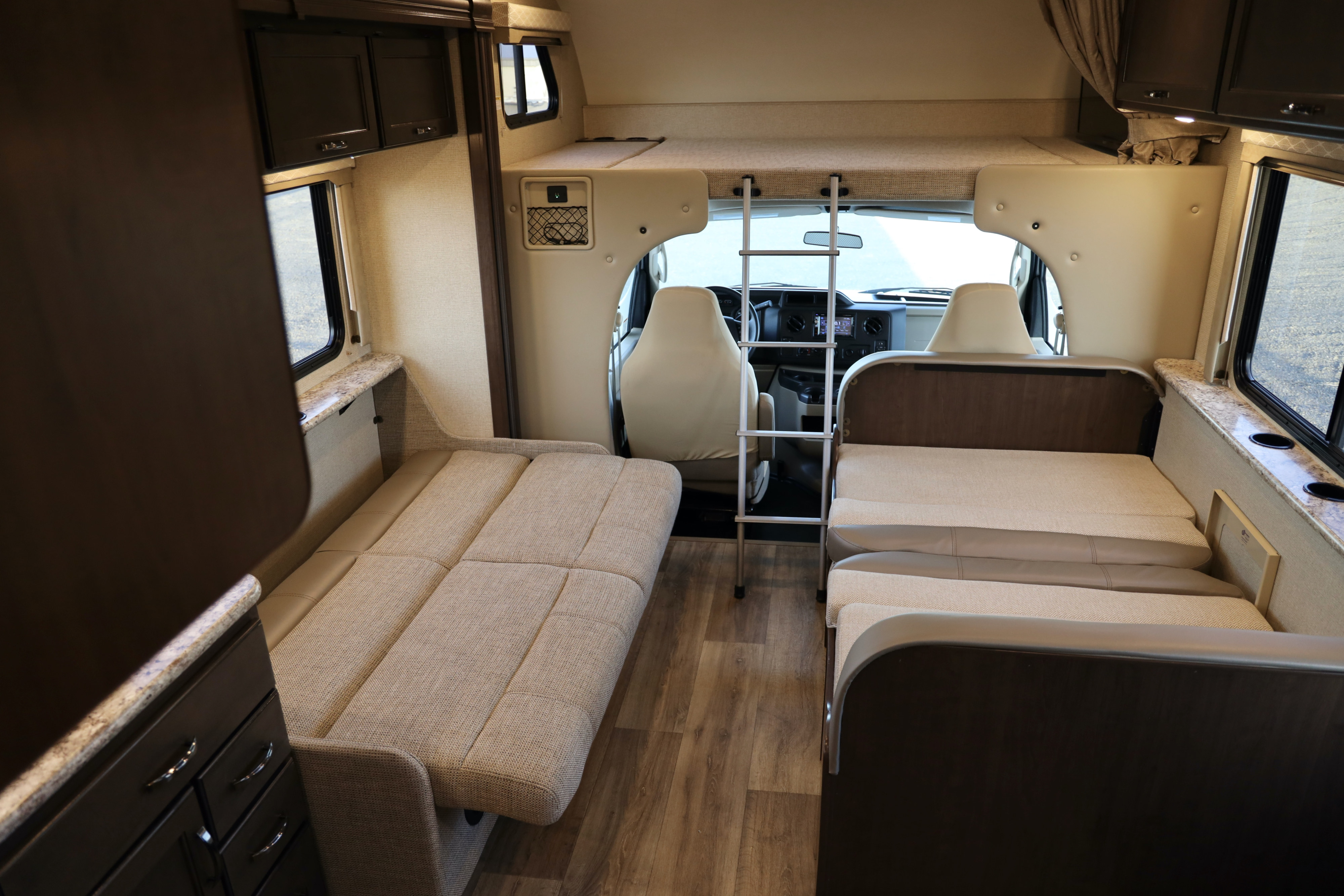 Inside an rv rental: convertible beds, ladder to an overhead bunk, and front cabin area.. Thor Freedom Elite 2019