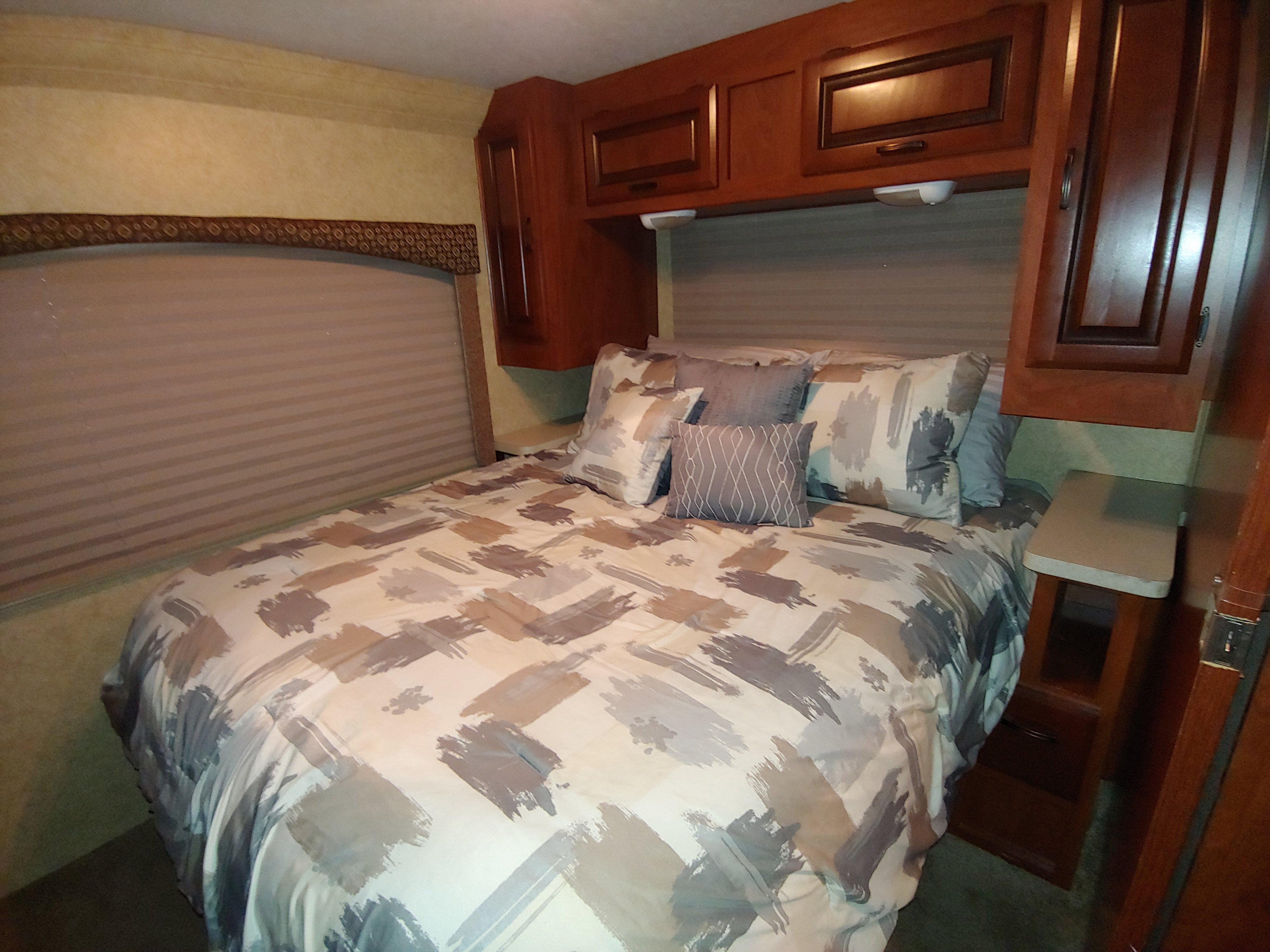 Comfort in this RV rental bedroom! Features a large bed with modern bedding, plush pillows, window blinds, and spacious cabinets.. Forest River Sunseeker 2012