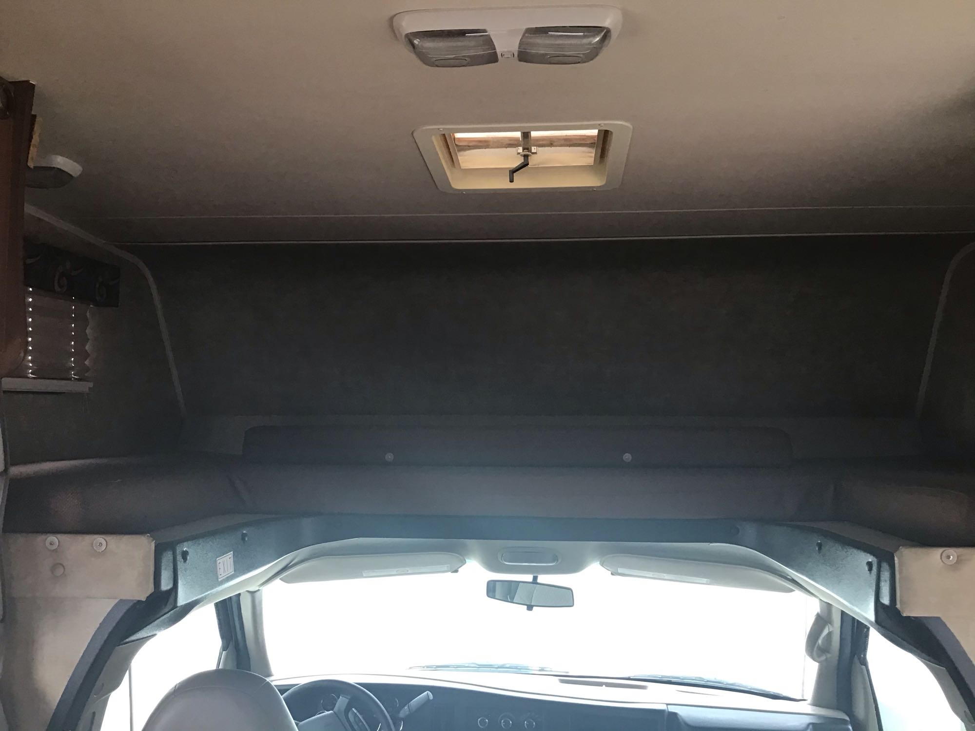 Inside an RV rental: a spacious cabover bunk is seen above the driver's area. Ceiling lights & roof vent are visible.. Other Other 2014