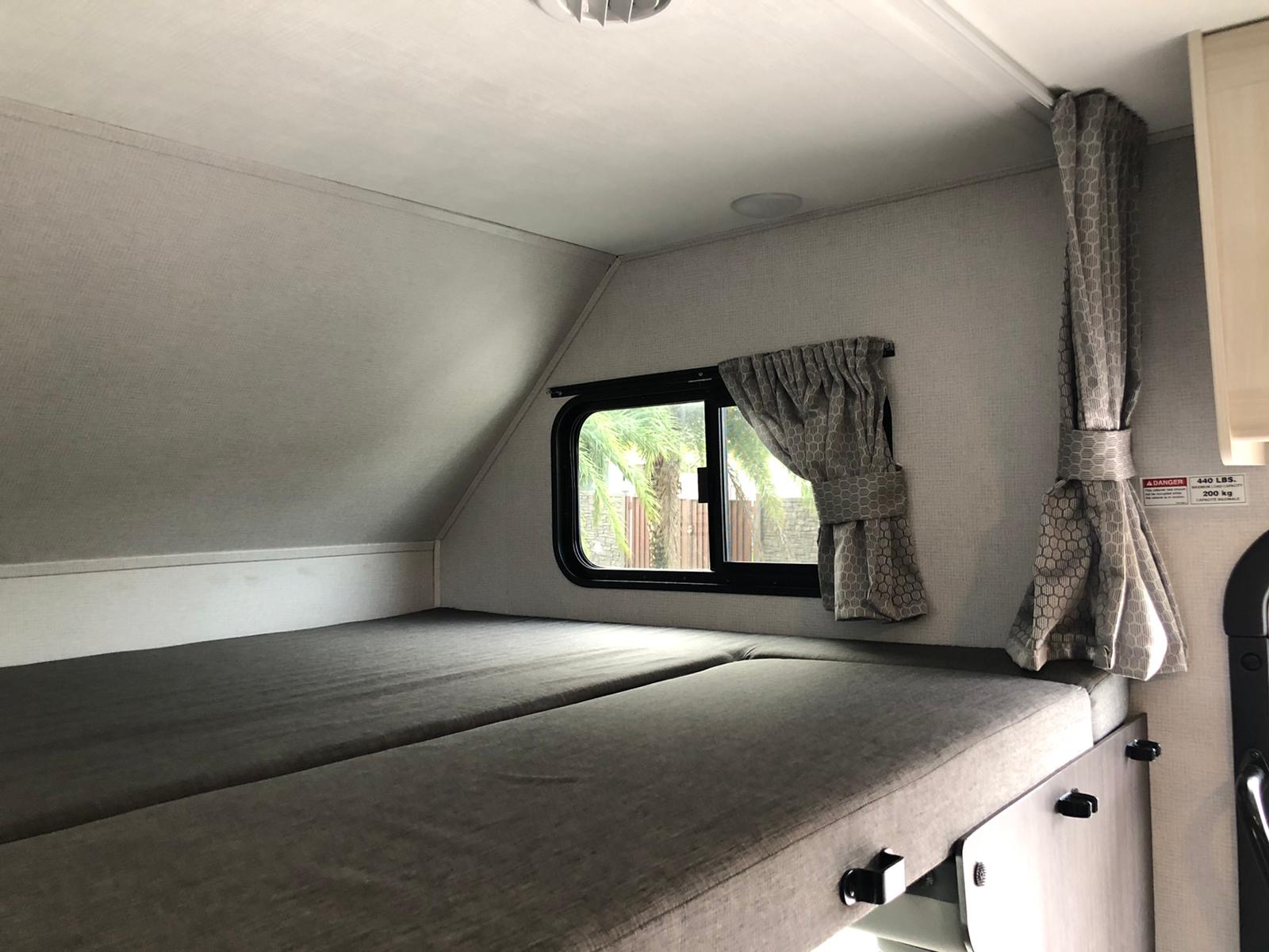 Cozy rv rental sleeping area with twin bunk beds, window, and privacy curtains. Max 440 lbs.. Ford E450 2020