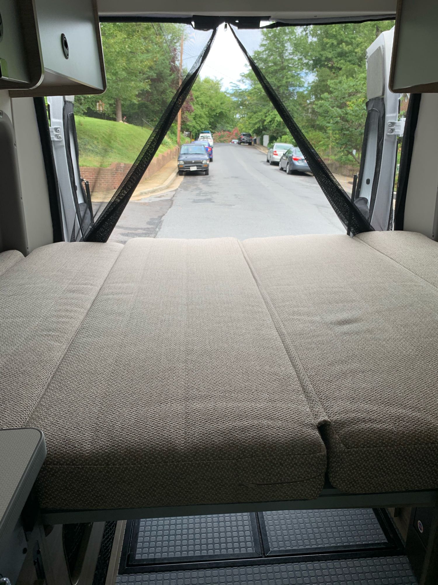 RV rental interior showing a comfortable bed and open rear doors with a mesh screen for fresh air and views.. Winnebago Solis 59p 2020