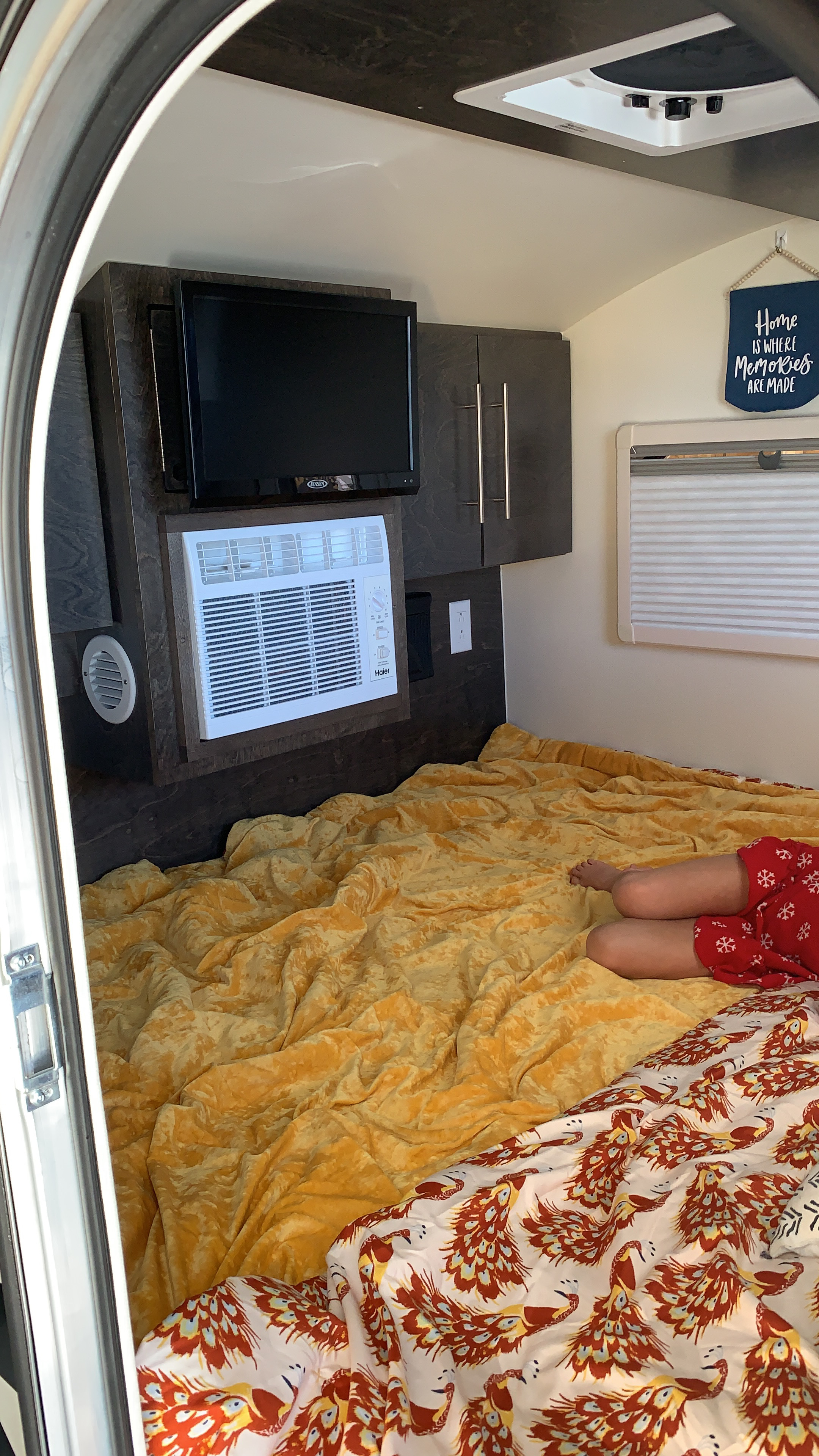 Cozy RV rental interior with a comfy bed, TV, AC, and a person relaxing. Great for travel!. T@G Txl 2020