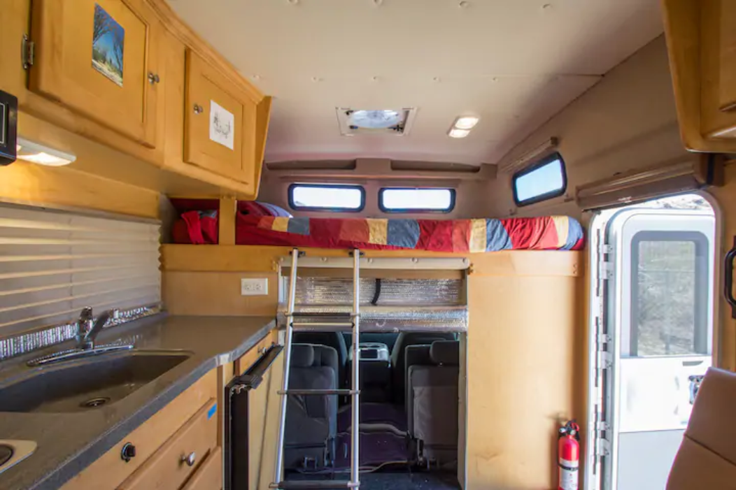 Spacious RV rental interior featuring a functional kitchenette, elevated bunk bed with ladder, and cozy mobile living space.. Tiger Adventure Vehicle Bengal 2016
