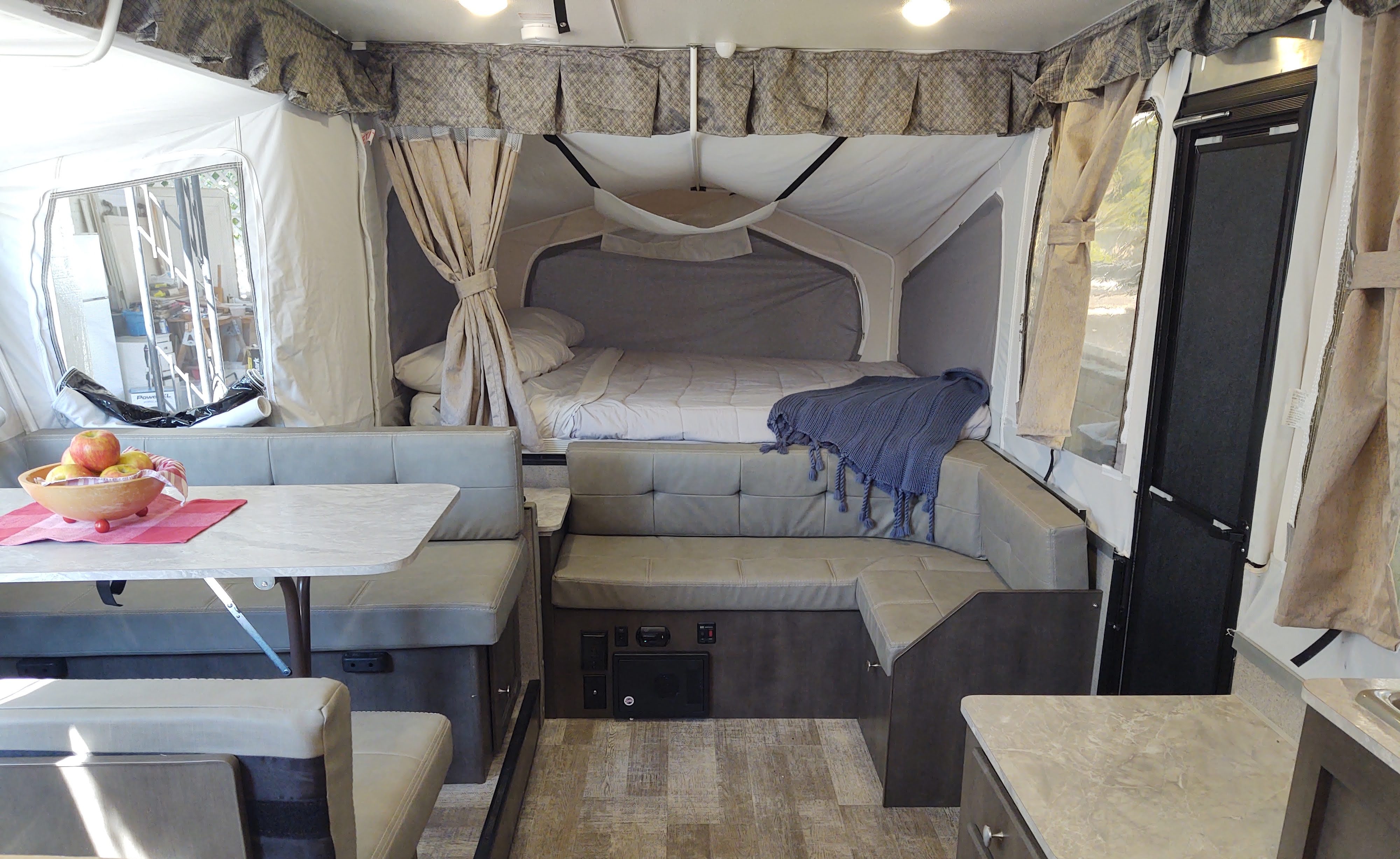 Explore this RV rental: bright pop-up camper interior with extended beds, dining area, and U-shaped lounge seating.. Forest River Rockwood Freedom 2021
