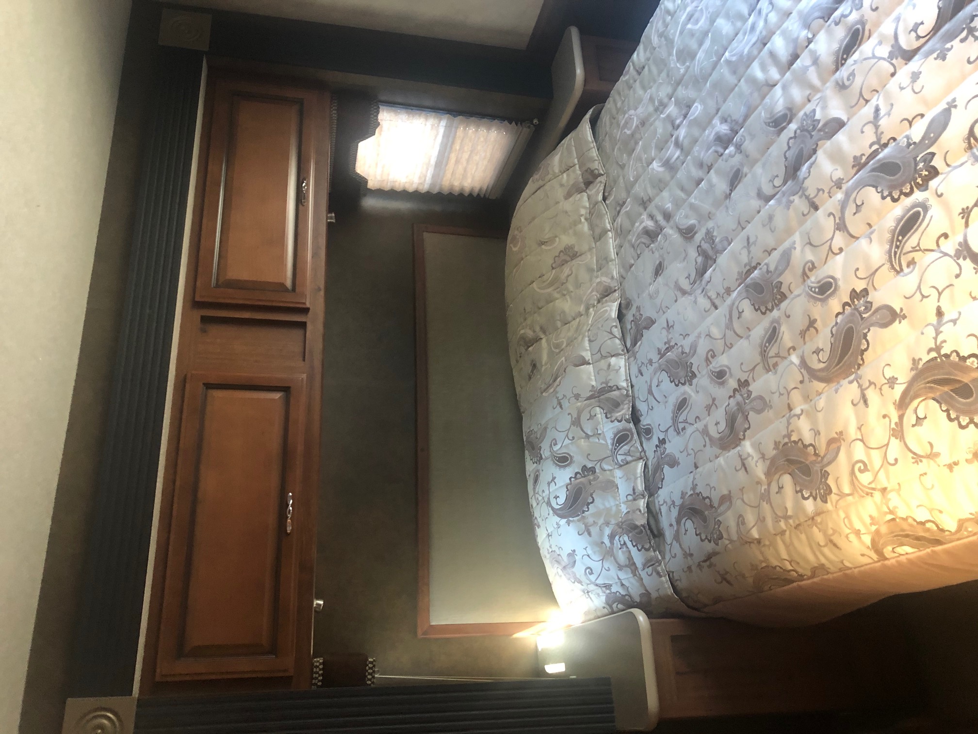 RV rental: Cozy bedroom interior with a patterned comforter, wood closet, and window. Enjoy compact comfort on your trip.. Fleetwood Jamboree Sport 2015