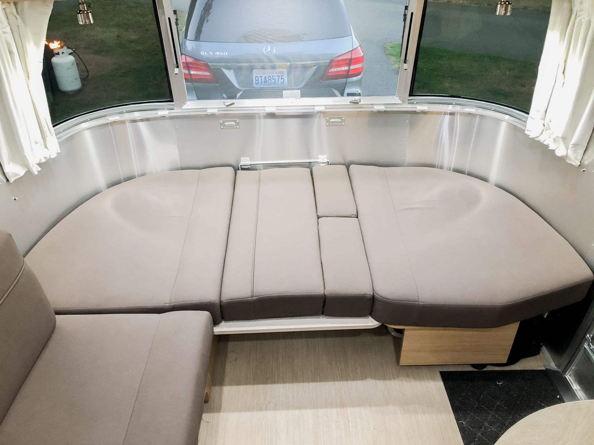 RV rental: Airstream interior with U-shaped lounge/bed and large rear window showing a Mercedes SUV & propane tank outside.. Airstream Flying Cloud 2020