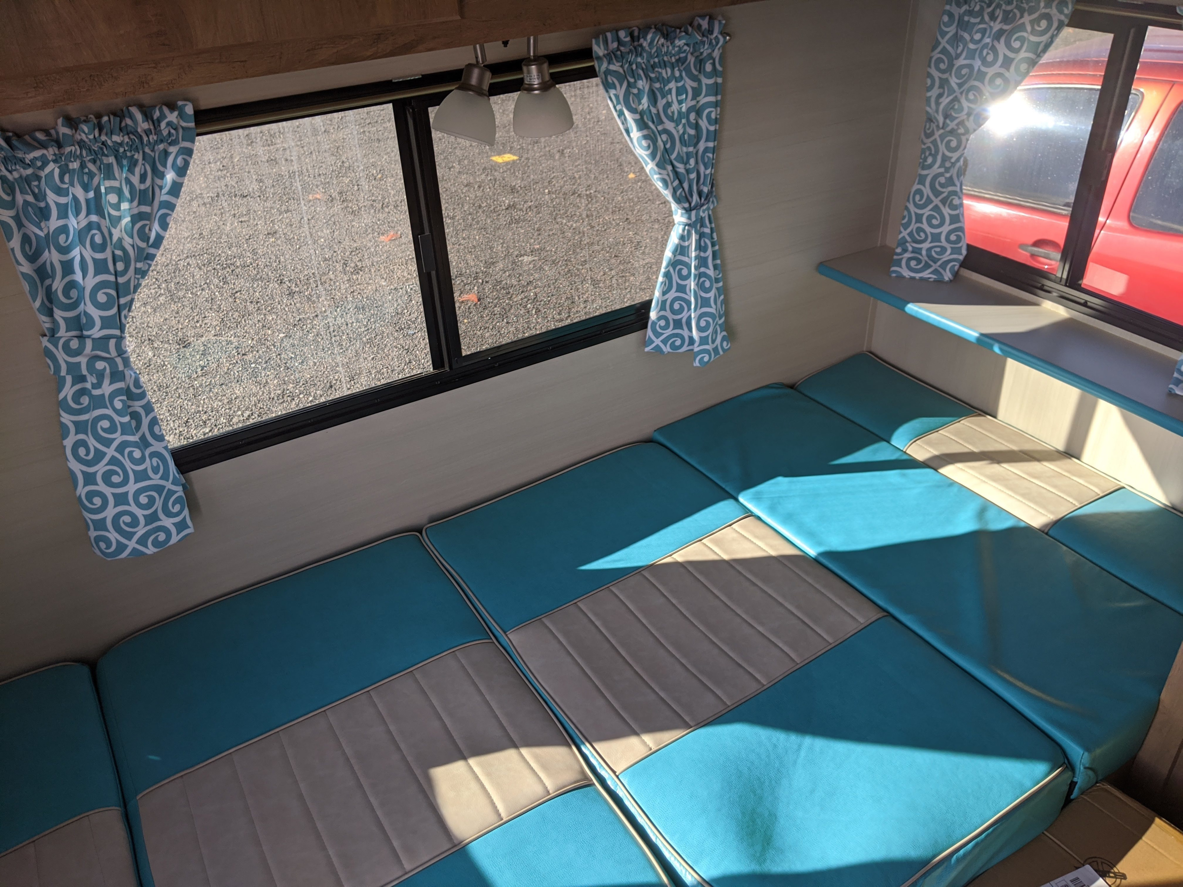 Bright RV rental interior featuring teal and tan cushions, patterned curtains, and windows with sunlight.. Gulf Stream Vintage Cruiser 2020