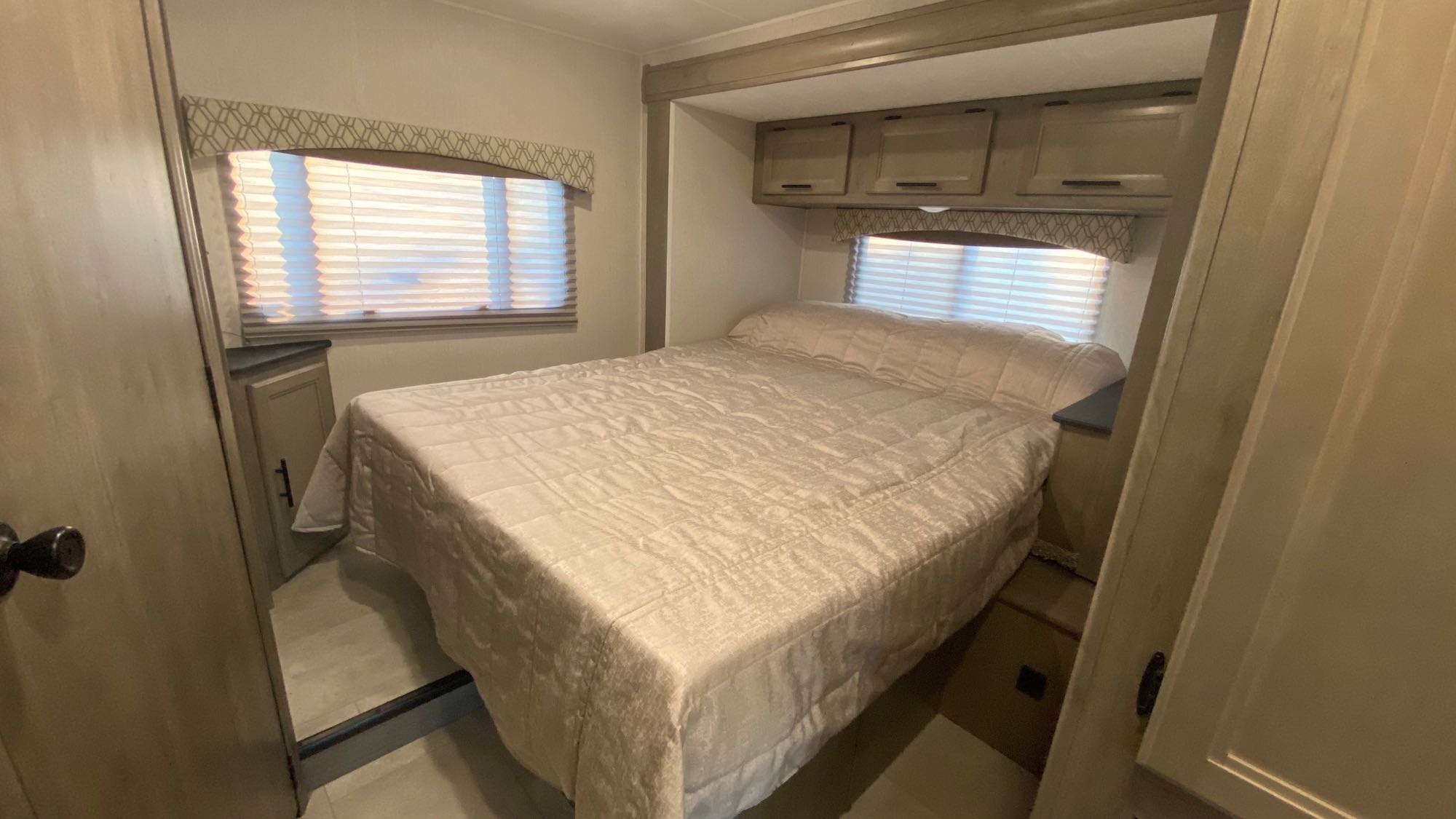 View this RV rental bedroom. It features a bed, two windows with blinds, and practical overhead storage for comfortable travel.. Coachmen Freelander 2021