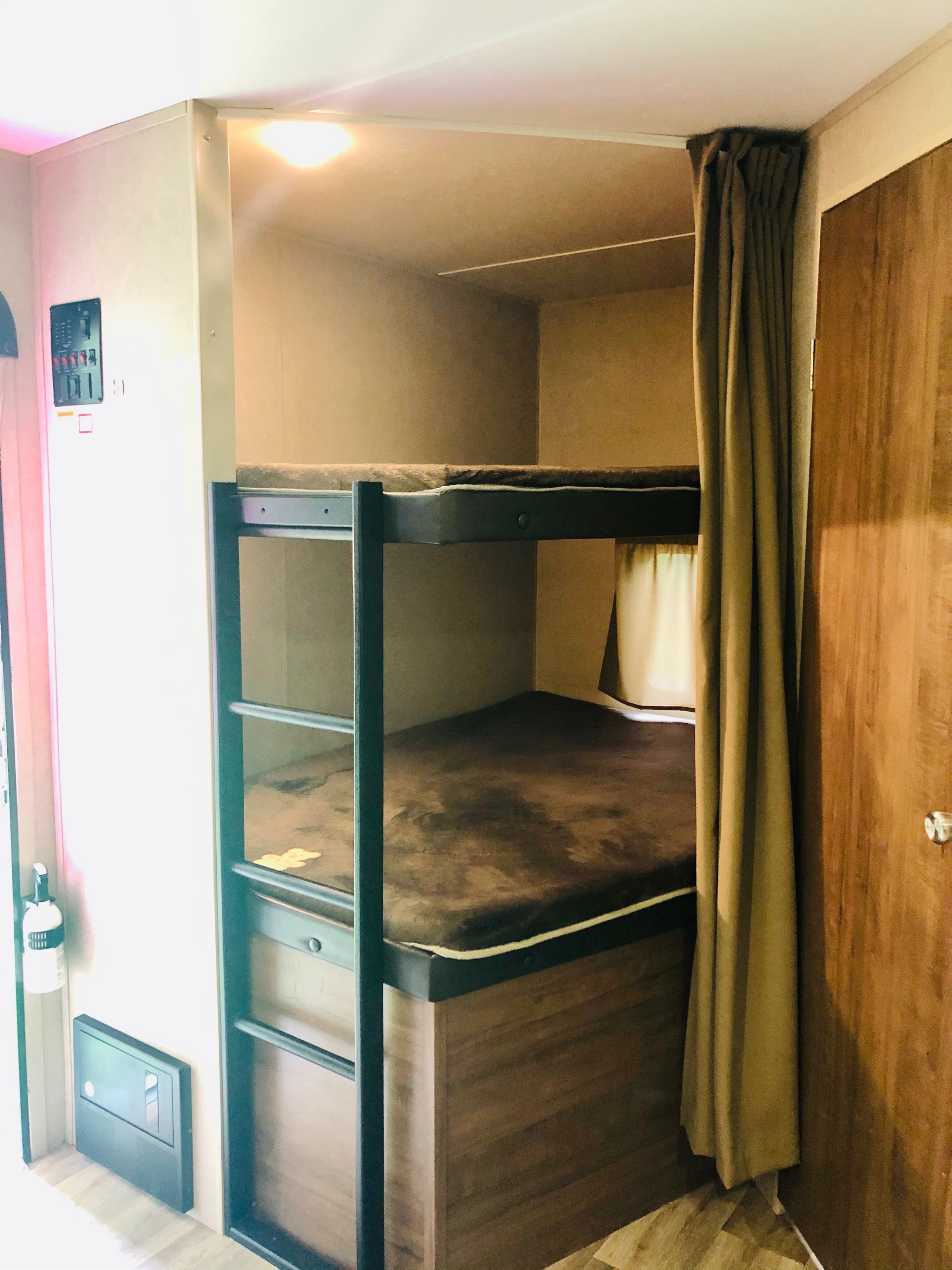 Cozy RV rental interior featuring bunk beds with privacy curtain, fire extinguisher, & electrical panel.. Dutchman Aspen Trail 2017