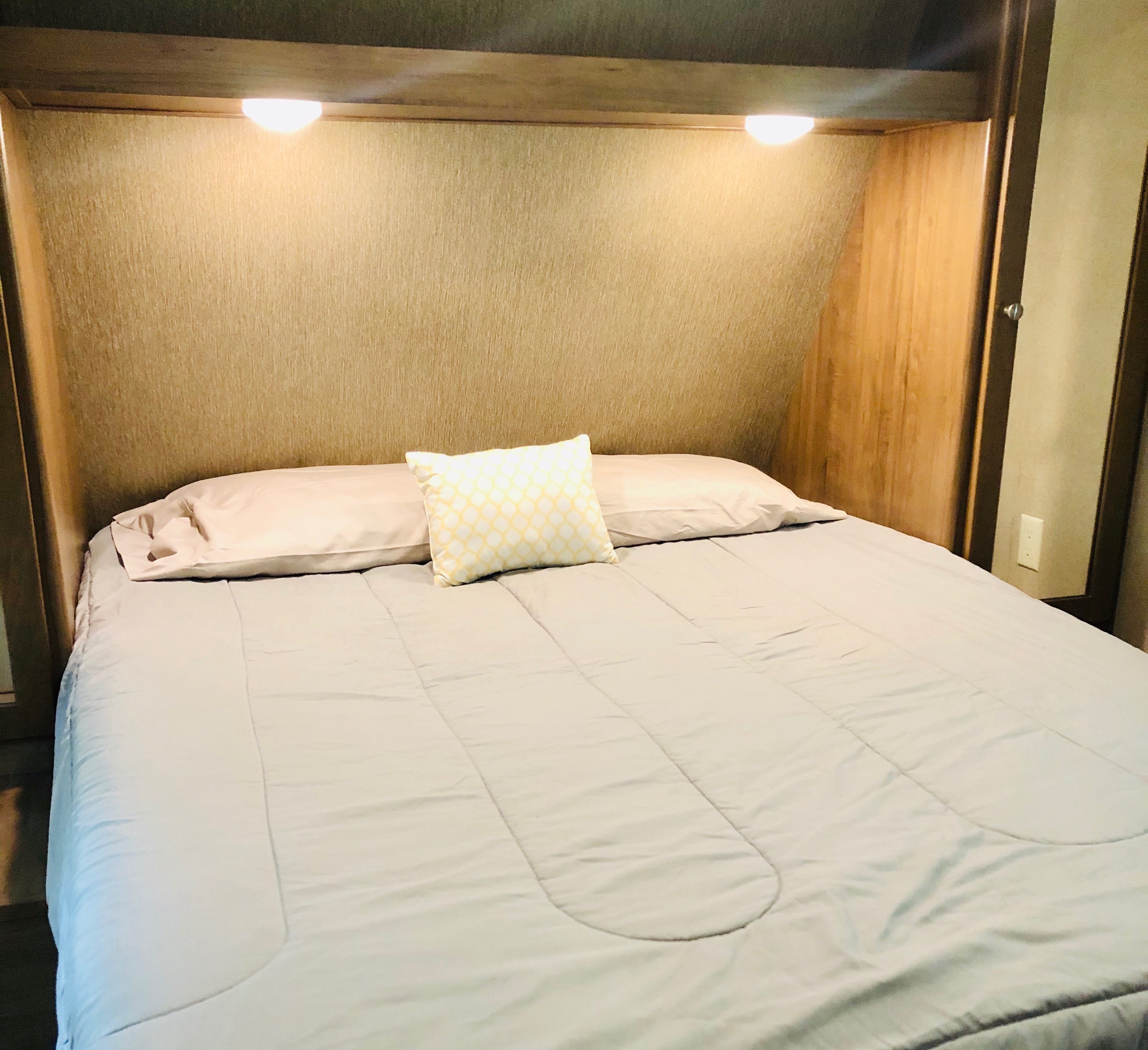 Cozy RV rental bedroom features a comfortable bed, built-in storage, and overhead reading lights.. Dutchman Aspen Trail 2017