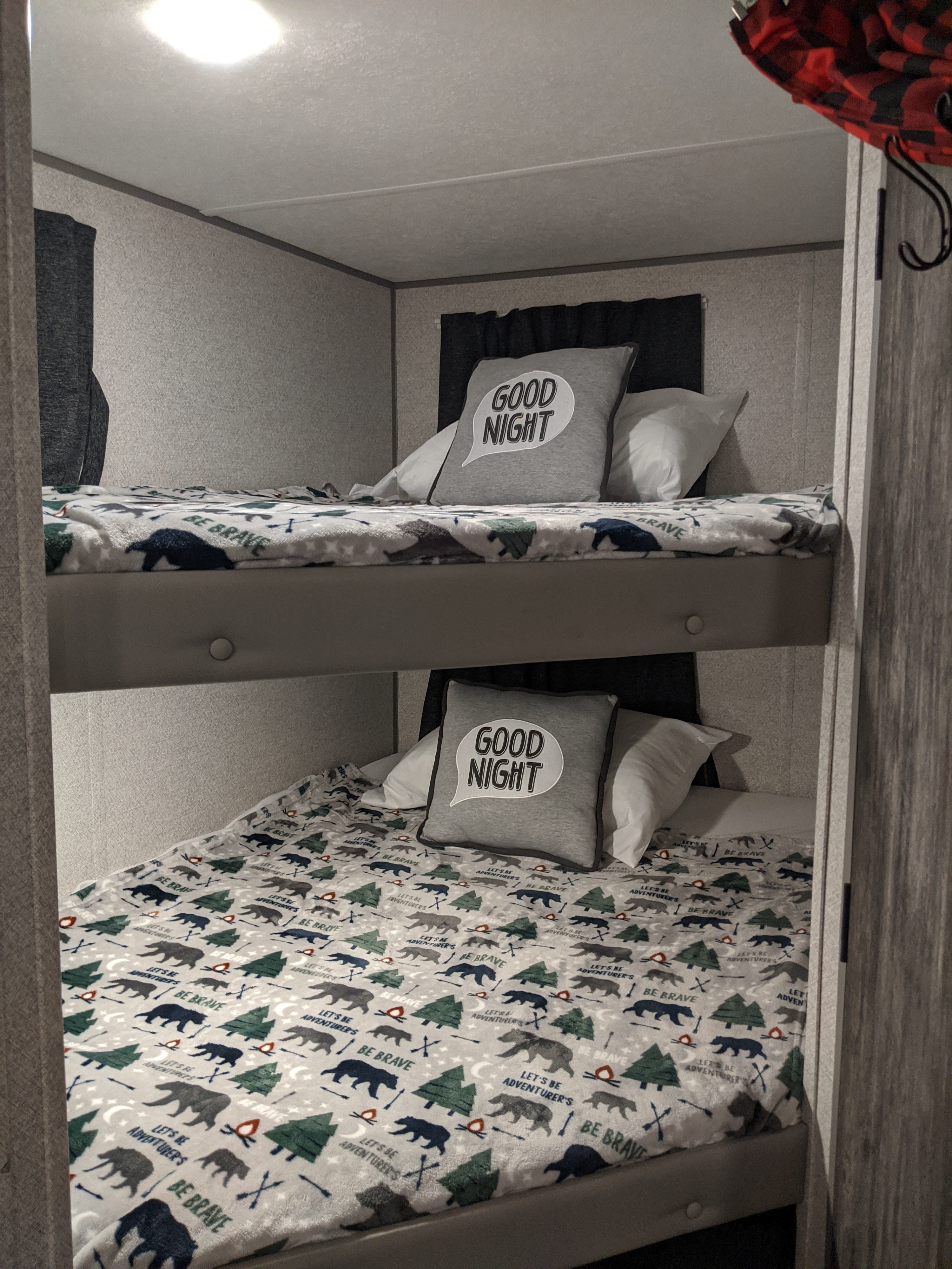 Cozy bunk beds ready for an RV rental adventure. Features "Good Night" pillows and "Be Brave" themed blankets.. Forest River Wildwood 2021