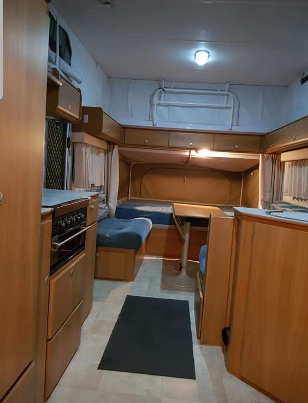 Experience comfort in this RV rental! Interior view with wood cabinetry, kitchen, dining area, and a pop-out sleeping bed.. jayco Expanda 2010