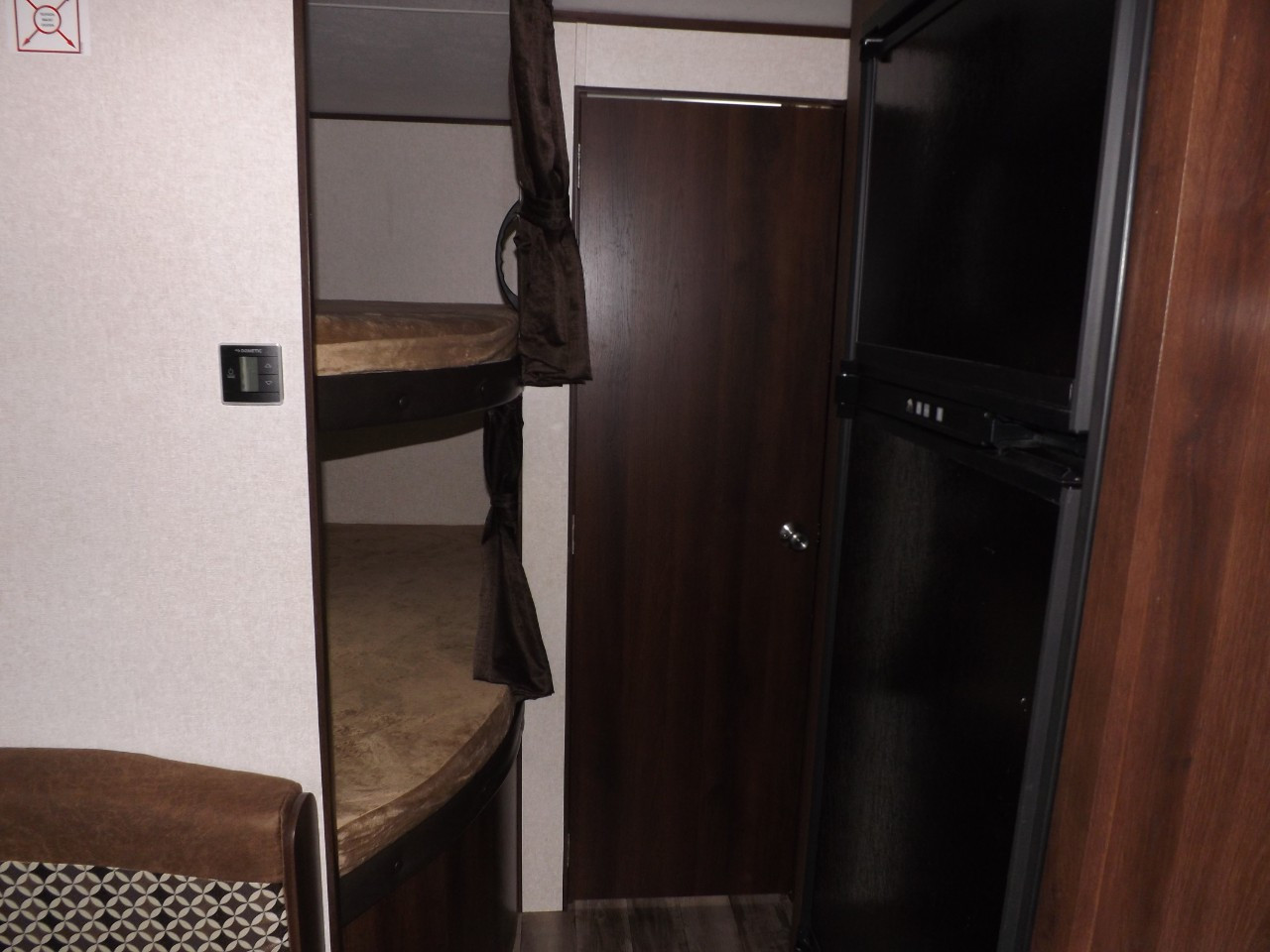RV rental interior featuring bunk beds, a compact refrigerator, and a Dometic climate control panel.. Jayco Jay Flight 2018