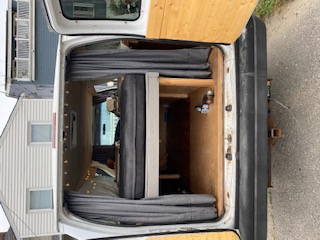 Back view of an **RV rental**: a converted camper van interior with a bed, storage, and wood paneling, ready for adventure travel.. Ford Econoline E250supercab 1999