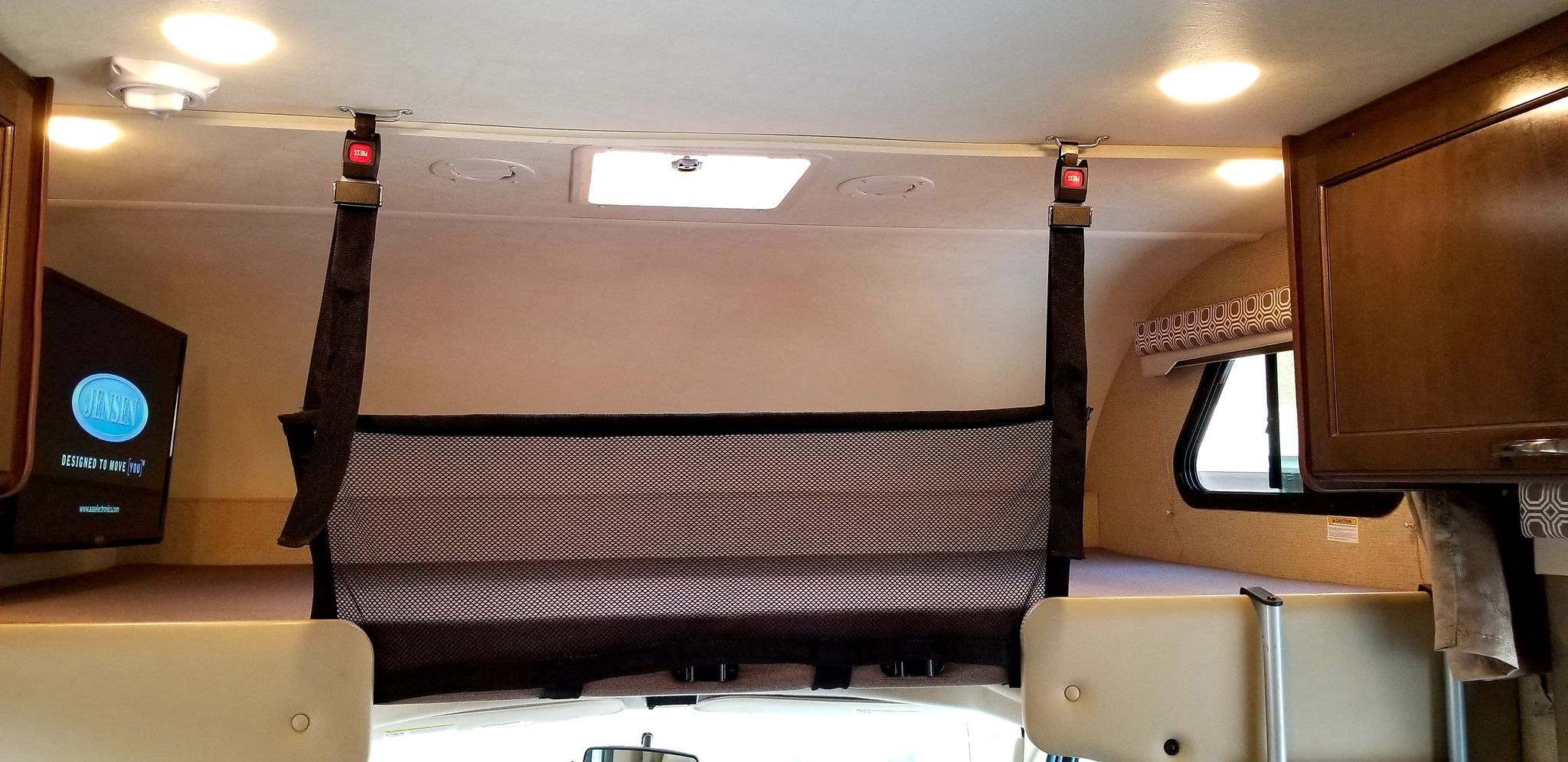RV rental overhead bunk area: A mesh safety net with seatbelt-style buckles secures the space. Features include a TV and ceiling lights.. Thor Four Winds 2020