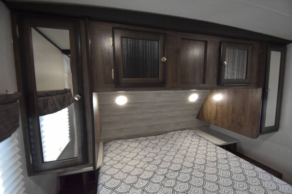 Compact RV rental bedroom with patterned bed, mirrored cabinets, and headboard lighting.. Other Other 2020