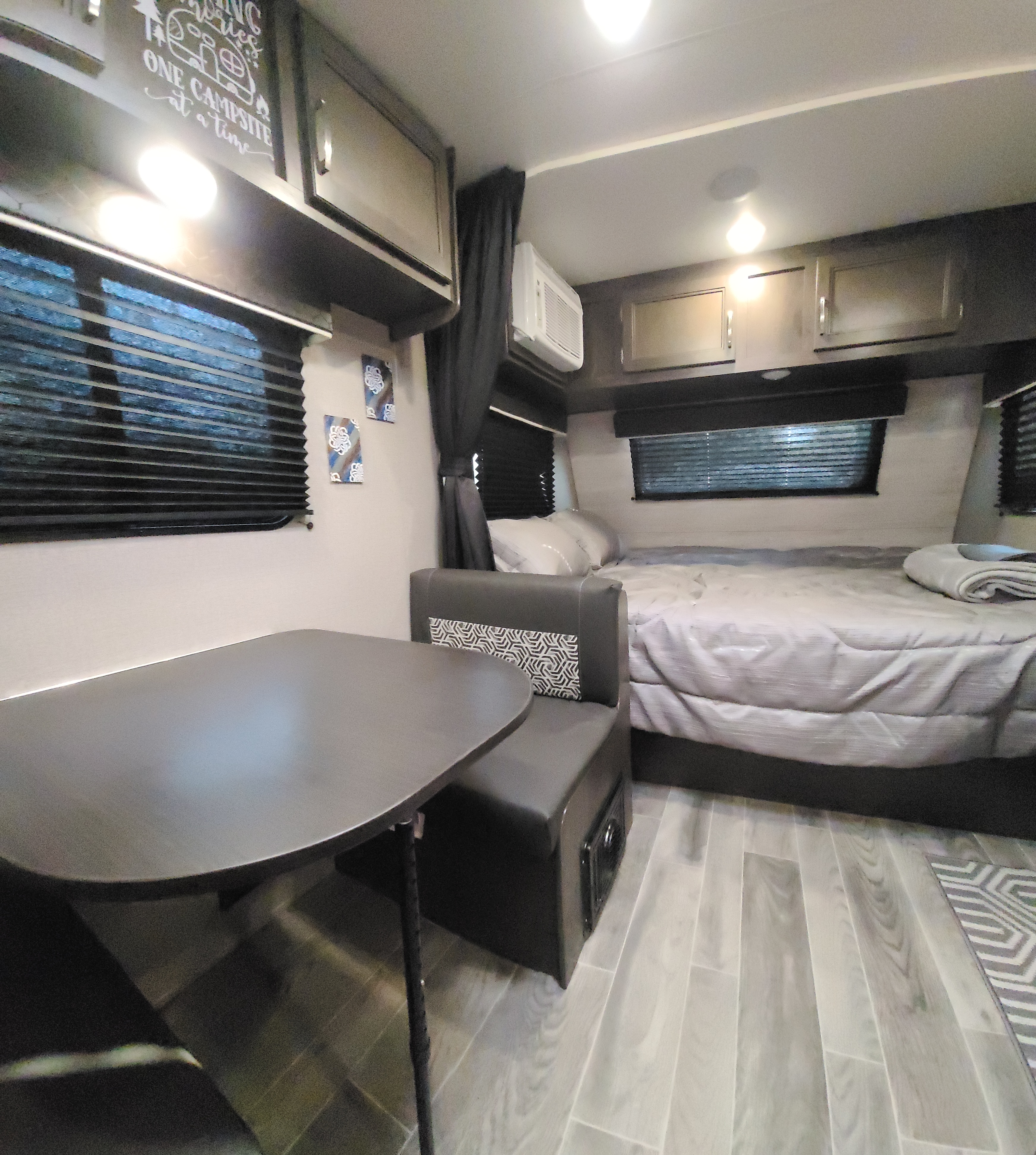 RV rental interior featuring a compact dining area, comfortable bed, and overhead storage cabinets.. Jayco Jay Flight 2021