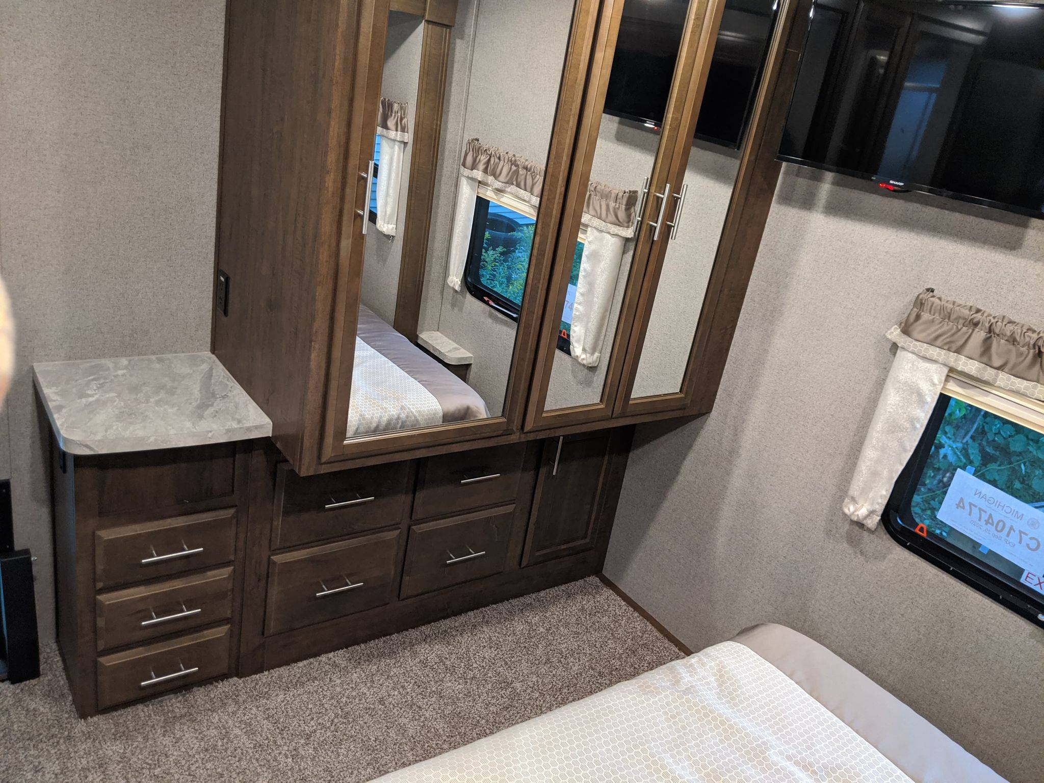 Inside an RV rental bedroom: Features a bed, mirrored wardrobe, dresser, and wall-mounted TV. Cozy and functional.. Forest River Forest River Flagstaff Classic Super Lite 2021