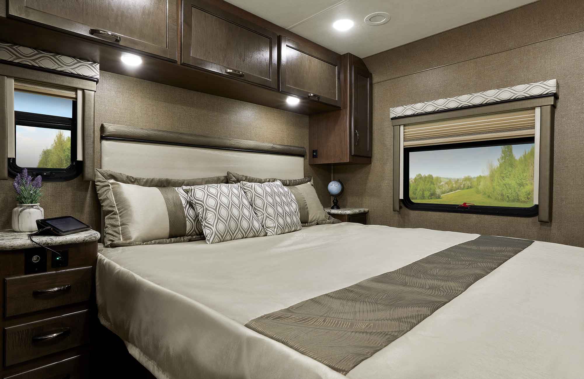 A serene RV rental bedroom featuring a large bed, ample storage, nightstands, and windows with scenic views.. Thor Motor Coach A32 Freedom Traveler 2020