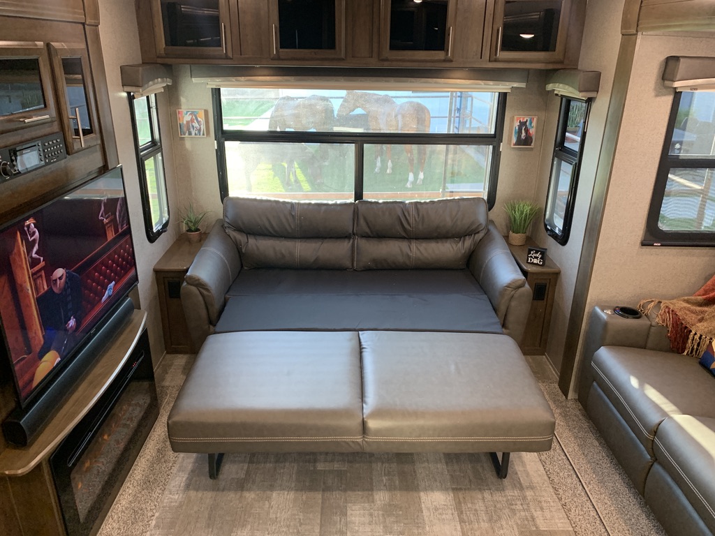 Comfortable RV rental interior with pull-out sofa, TV, and scenic views of horses outside. Perfect for your next adventure!. Forest River Rockwood Signature 2021