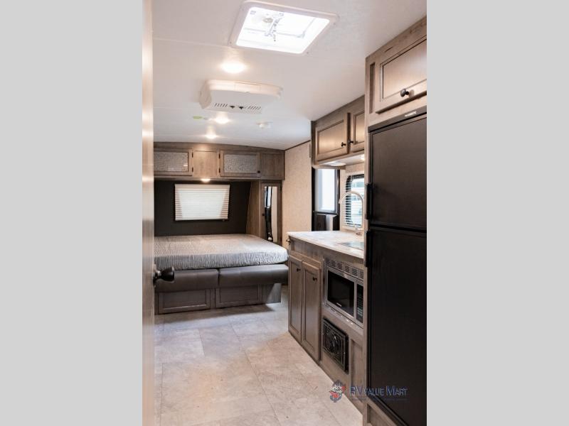 Explore in comfort! This RV rental features a cozy bedroom area and a compact kitchen with appliances.. Coachmen Apex 2021