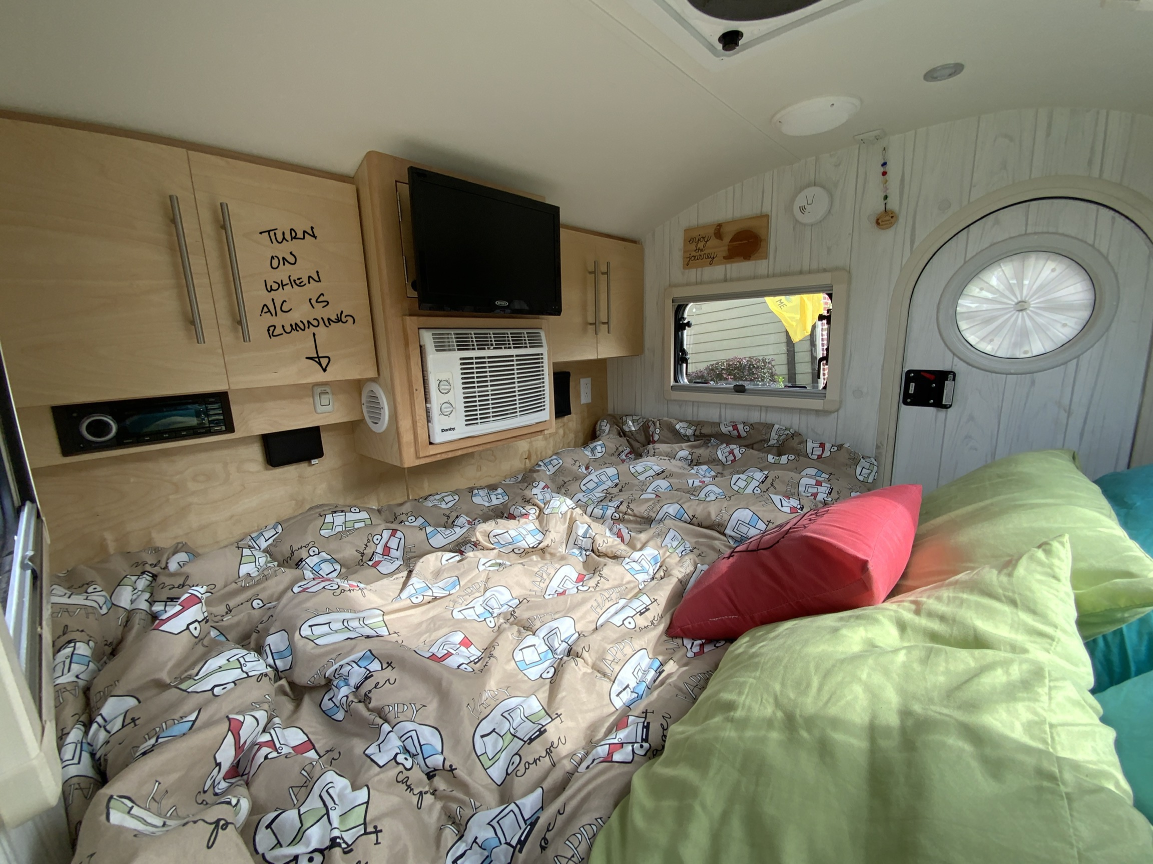 Cozy RV rental interior with a comfy bed, AC, TV, and wooden cabinets; ready for your next adventure.. nuCamp T@G 2019