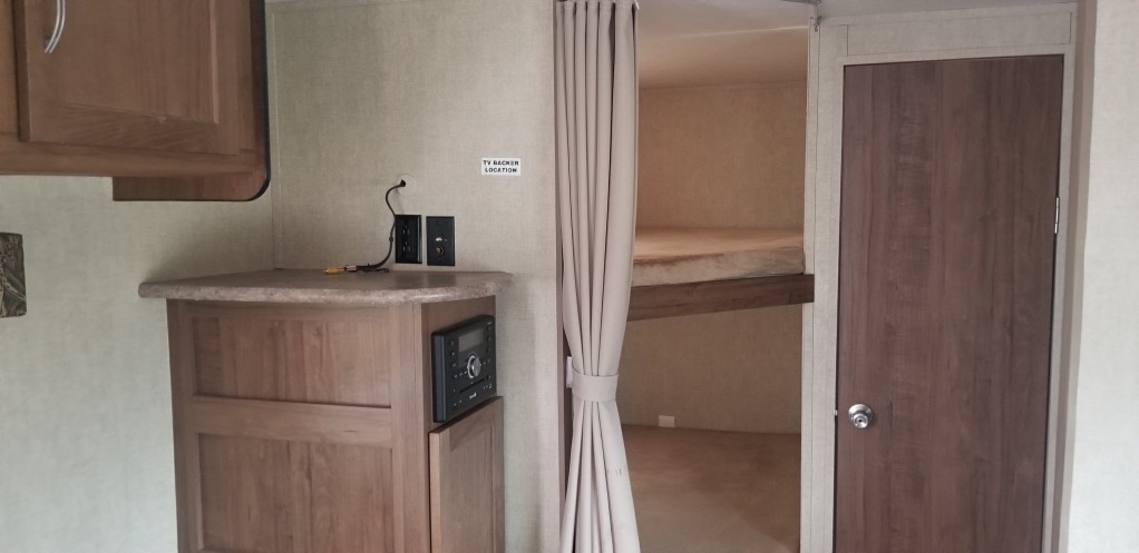 View inside an RV rental showing bunk beds, an entertainment area with TV connections, and storage cabinets.. Gulf Stream Trailmaster 2018