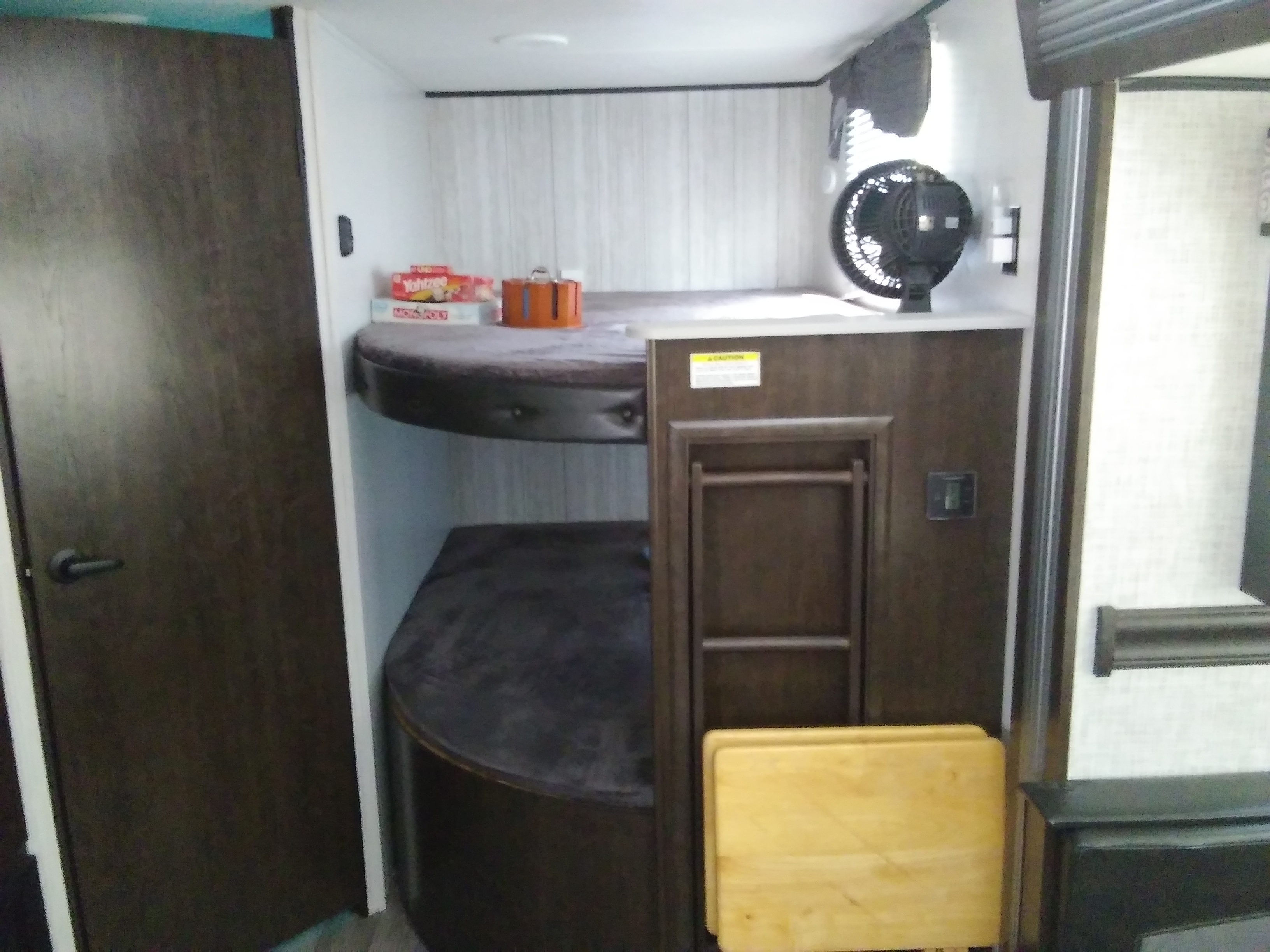 Cozy RV rental bunk beds, perfect for kids, featuring games (Monopoly, Yahtzee), a fan, and an access ladder.. Heartland Pioneer 2021