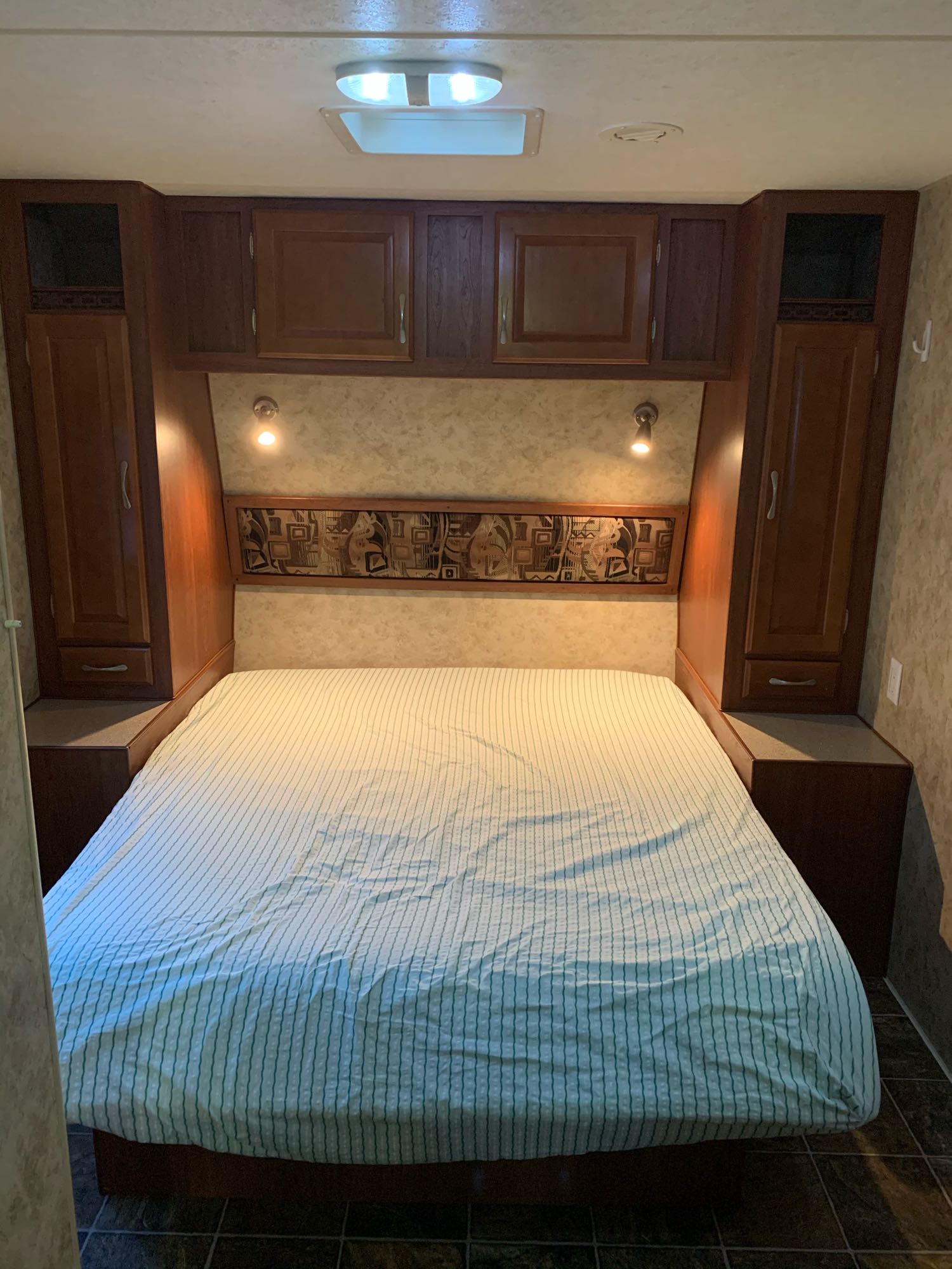 Step into comfort: This inviting RV rental bedroom features a cozy bed, ample storage, and warm lighting for your journey.. Snowriver Snow River 2011