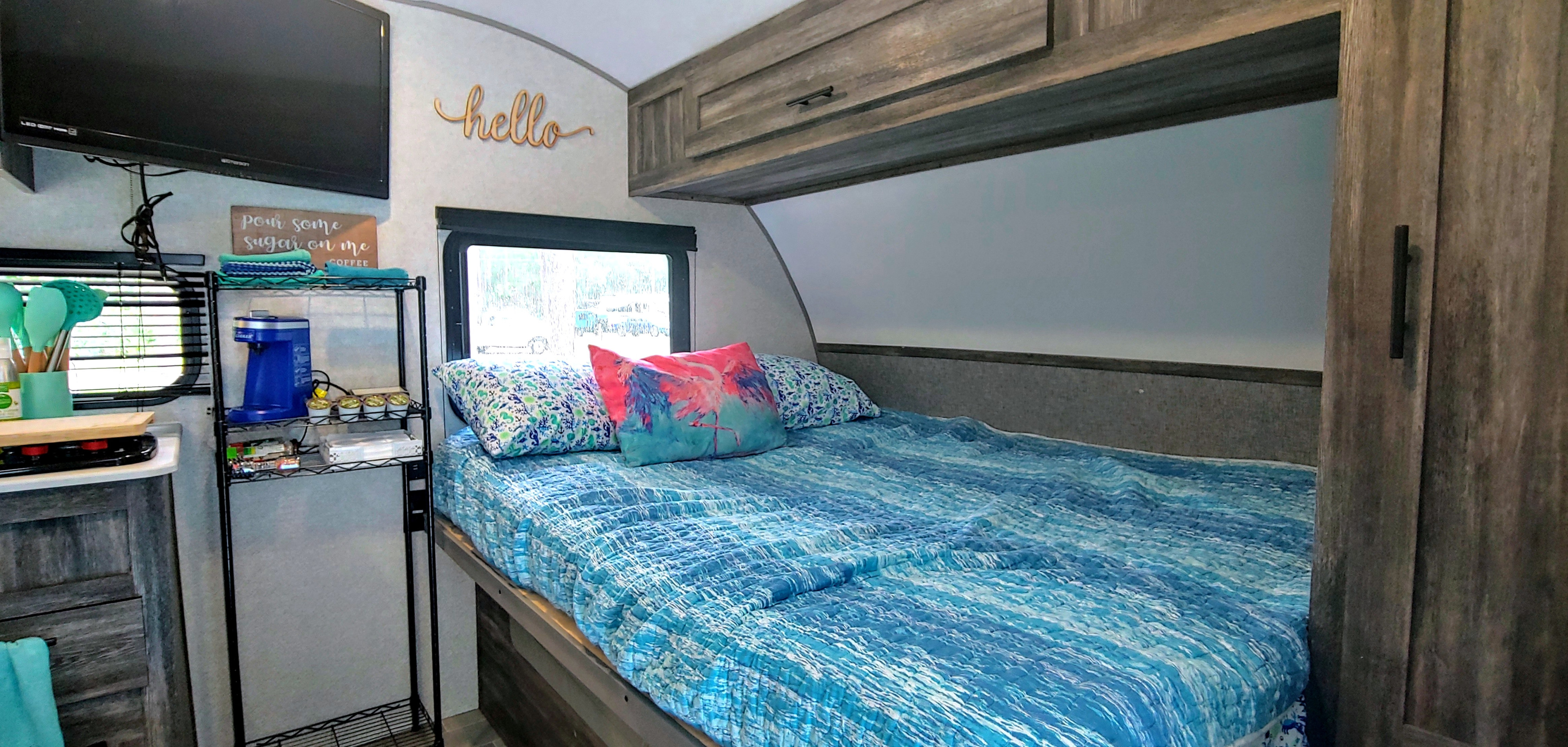 Compact RV rental bedroom with blue bedding, a TV, and coffee nook, ideal for travel adventures.. Forest River Salem 2020