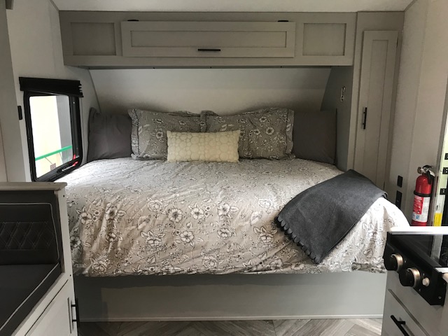 RV rental interior: Cozy camper bedroom featuring a queen bed, overhead storage, and patterned bedding for a comfortable stay.. Forest River Other 2021