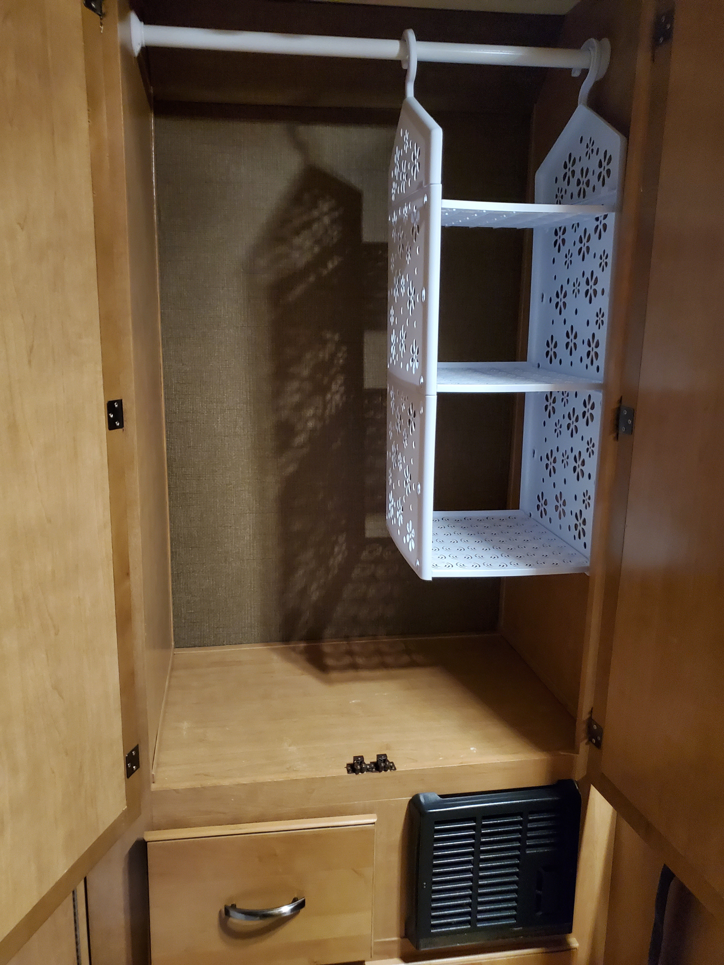 Compact RV rental closet featuring a white hanging shelf organizer, plus a lower drawer and vent for efficient storage.. Thor Motor Coach Freedom Elite 2015