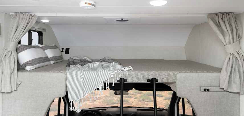 Spacious cab-over bunk in an RV rental, featuring a bed with pillows, blanket, and curtains for a cozy sleeping area.. Winnebago Vita 2020