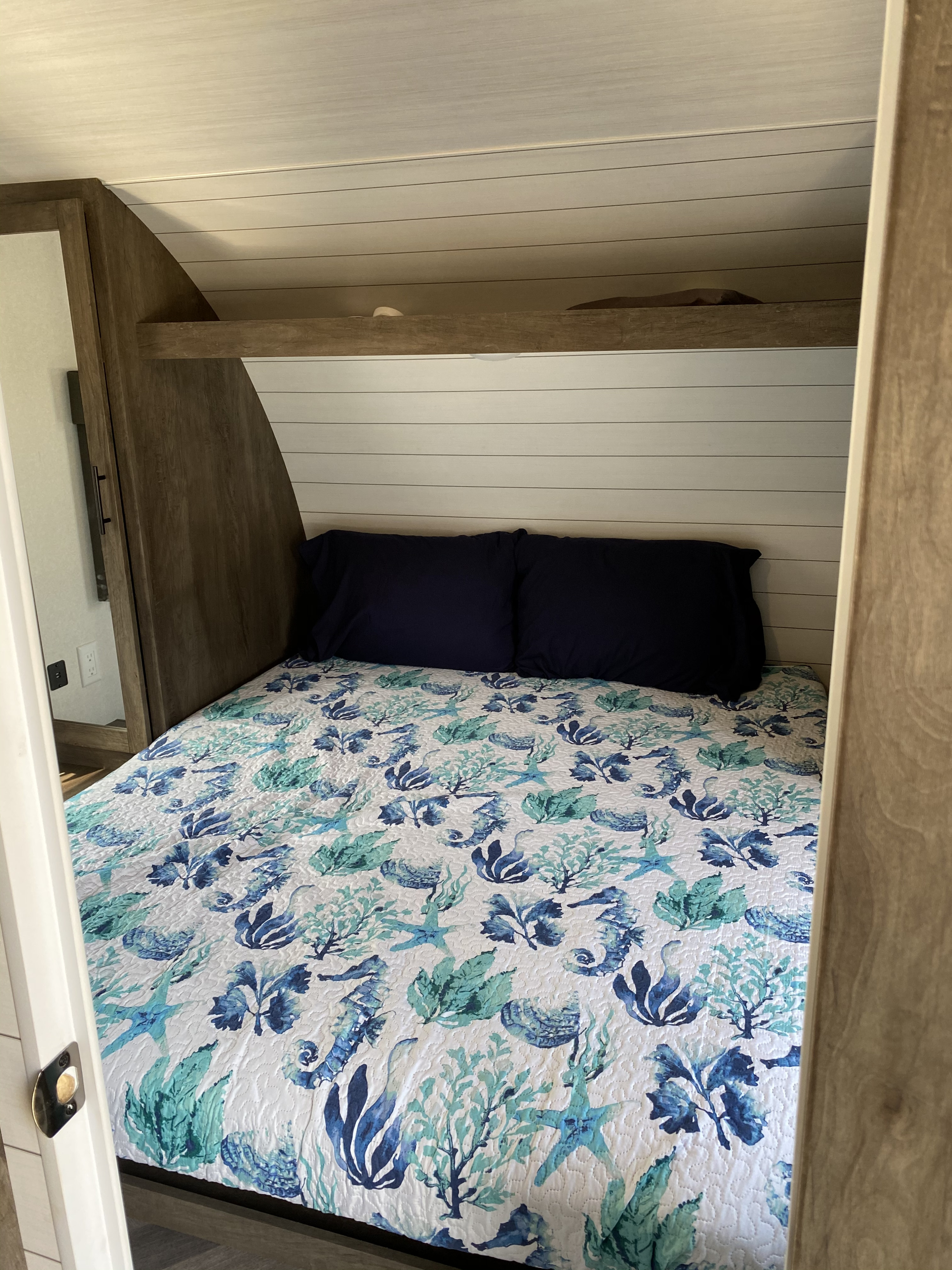 Cozy RV rental bedroom with shiplap walls & a marine-themed quilt. Built-in storage adds to the compact design.. Forest River Salem Cruise Lite 2021