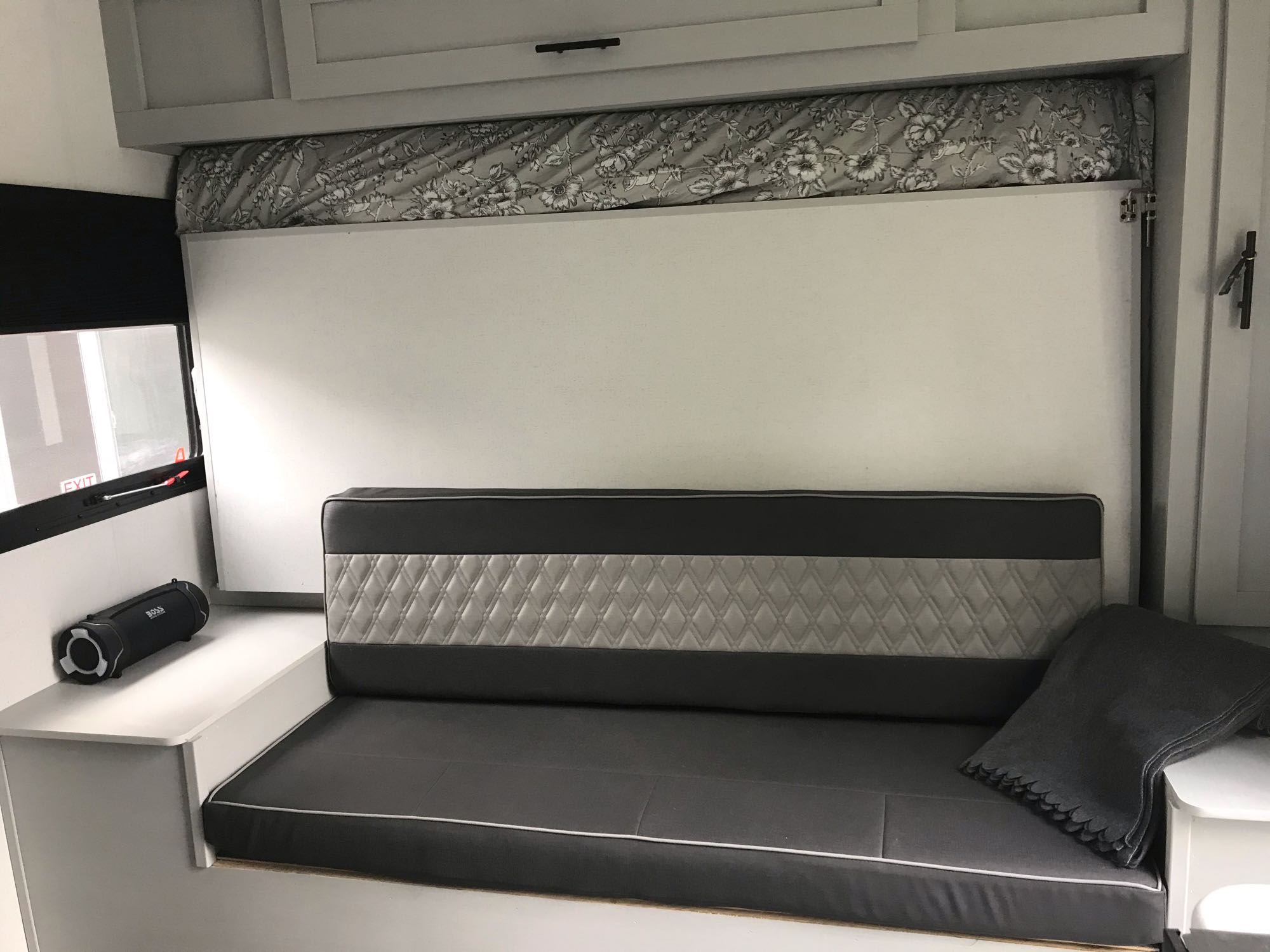 This RV rental features a gray convertible sofa bed, ideal for compact travel. A speaker is on the left shelf.. Forest River Other 2021