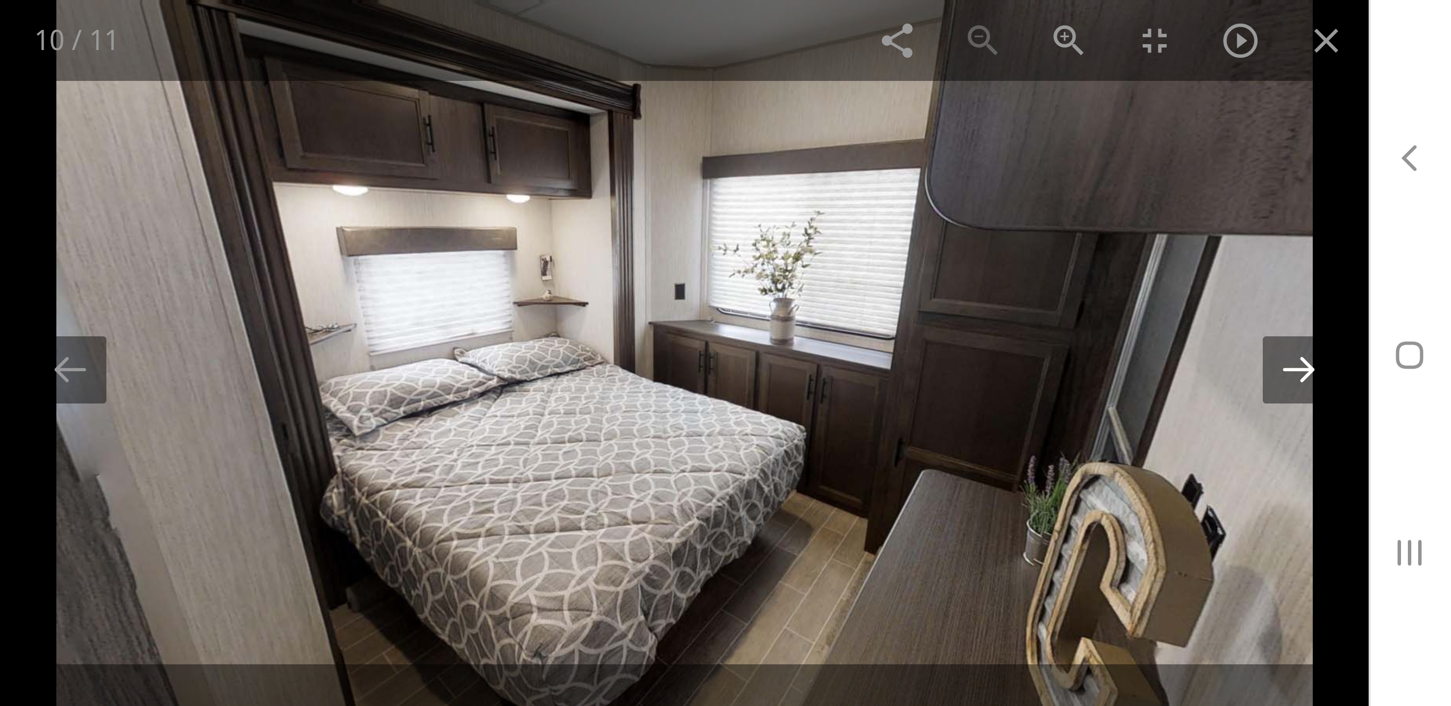 Comfortable RV rental bedroom with a patterned bed, overhead cabinets, and bright windows, providing cozy accommodations for your trip.. forest river cherokee 39ca 2019