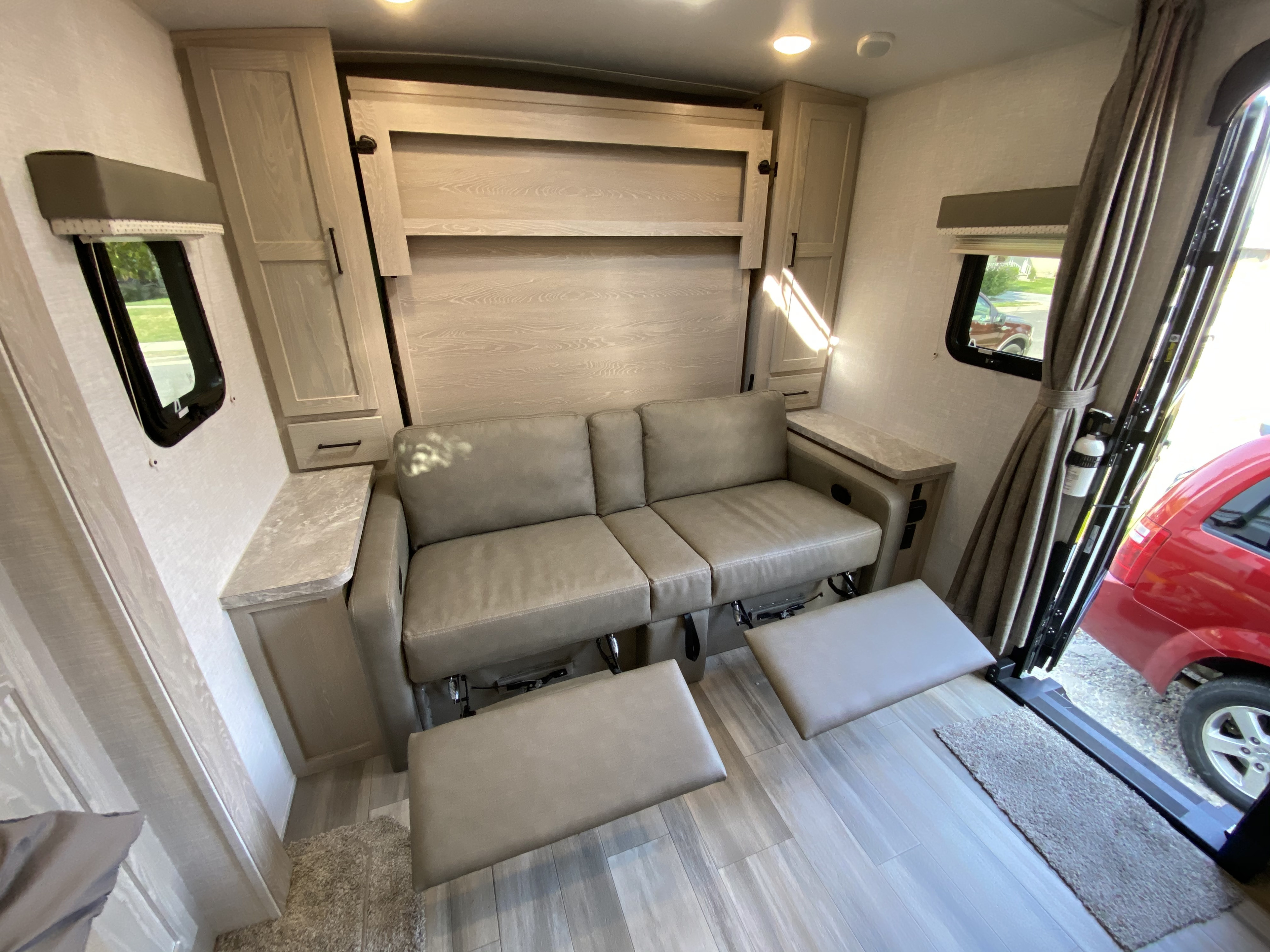 RV rental toy hauler interior: versatile sofa, wall-mounted Murphy bed, and light-toned cabinetry in a bright space.. Forest River Mini-Lite 2021