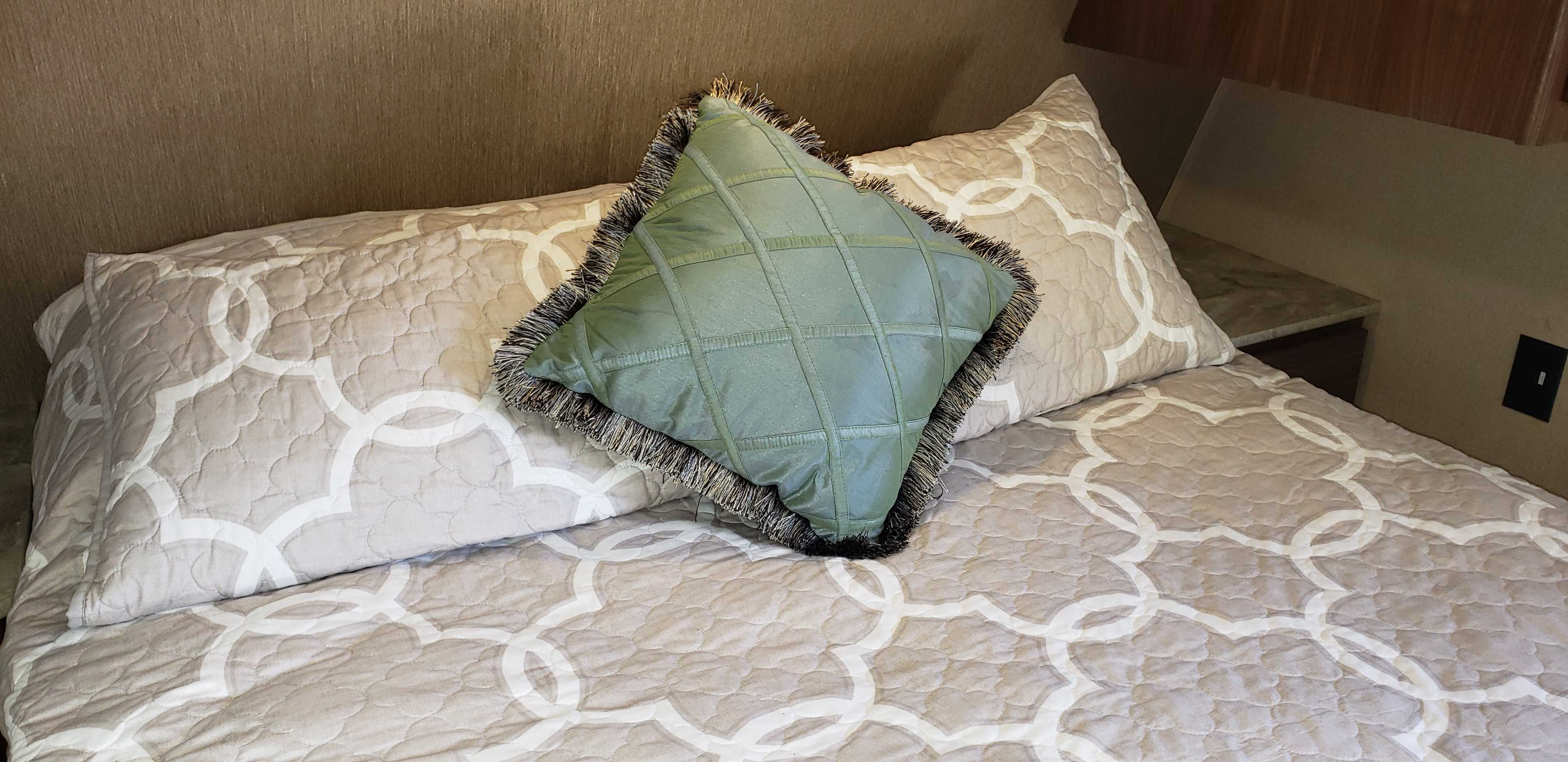 Cozy rv rental bedroom details: patterned beige bedding and a distinctive green fringed throw pillow.. Coleman Coleman 202RD 2017