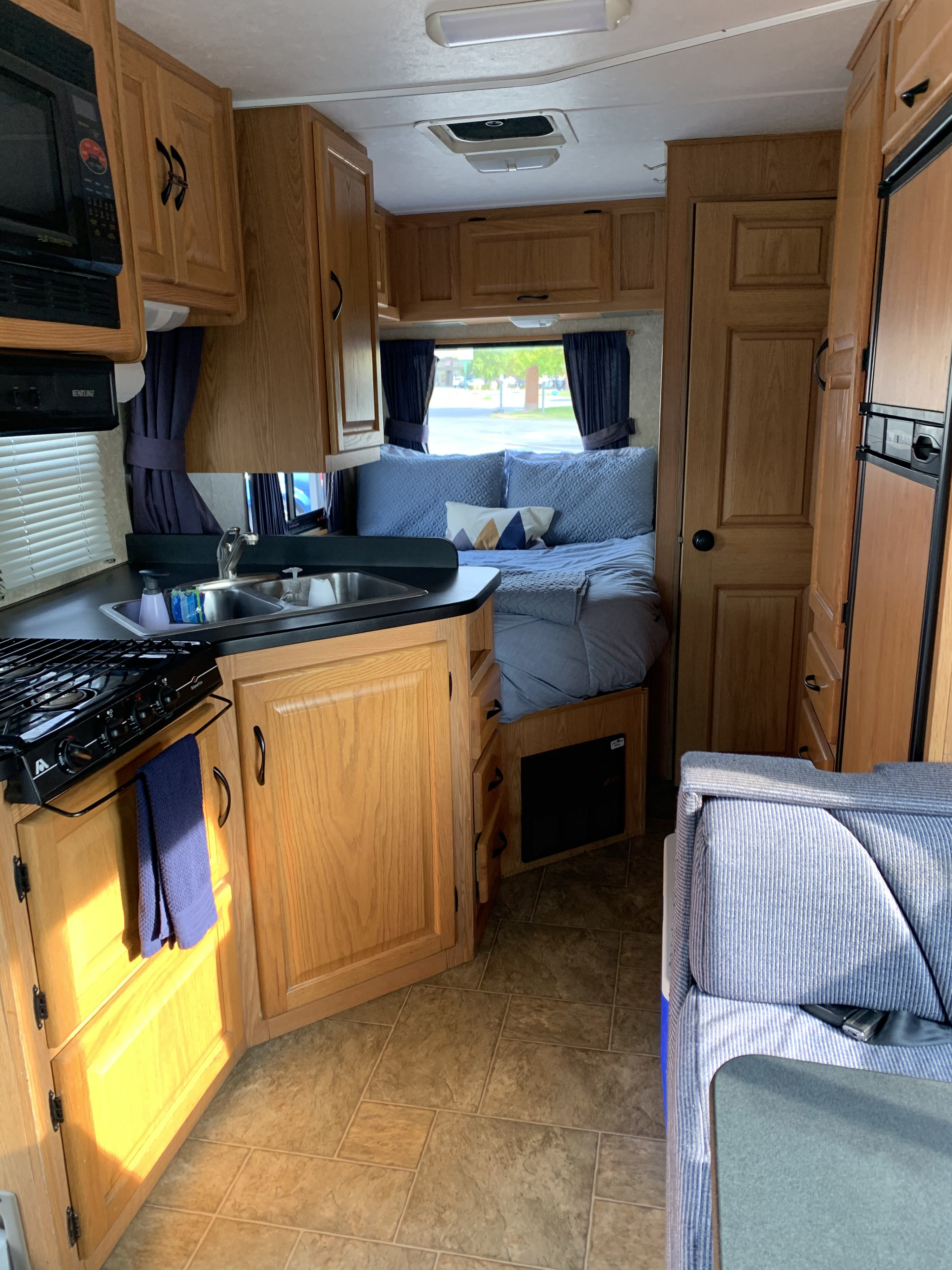 Cozy rv rental interior: kitchen, bedroom, and living area with wood cabinets and blue accents.. Majestic Leisure Craft Tourer Ii 2007