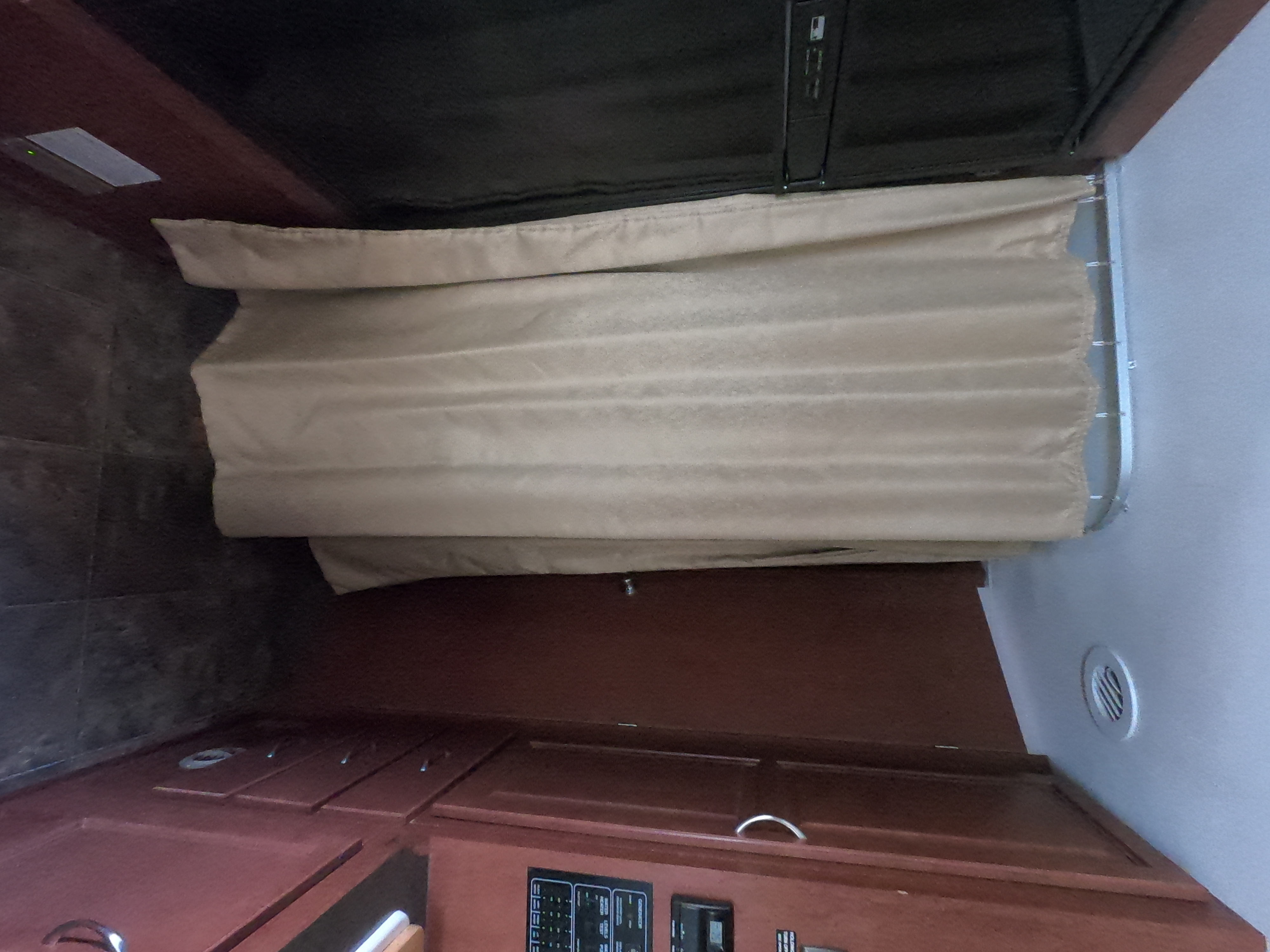 Inside this RV rental, a tan curtain divides space, complemented by rich wood cabinetry and a fridge. Comfortable travel.. Winnebago Minnie Winnie 2014