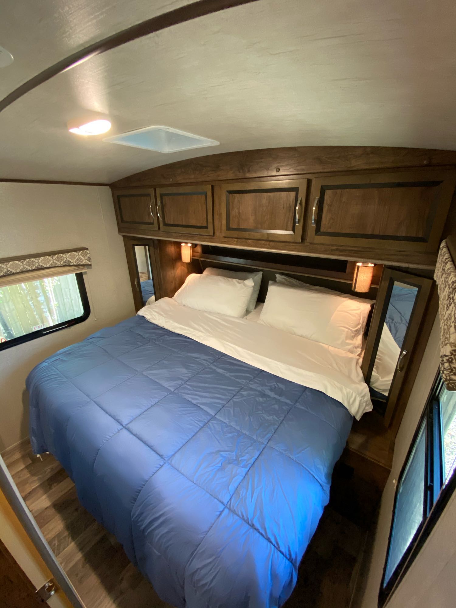 Cozy RV rental bedroom with a comfy bed, overhead storage, windows for natural light, and bedside mirrors.. Other Other 2018
