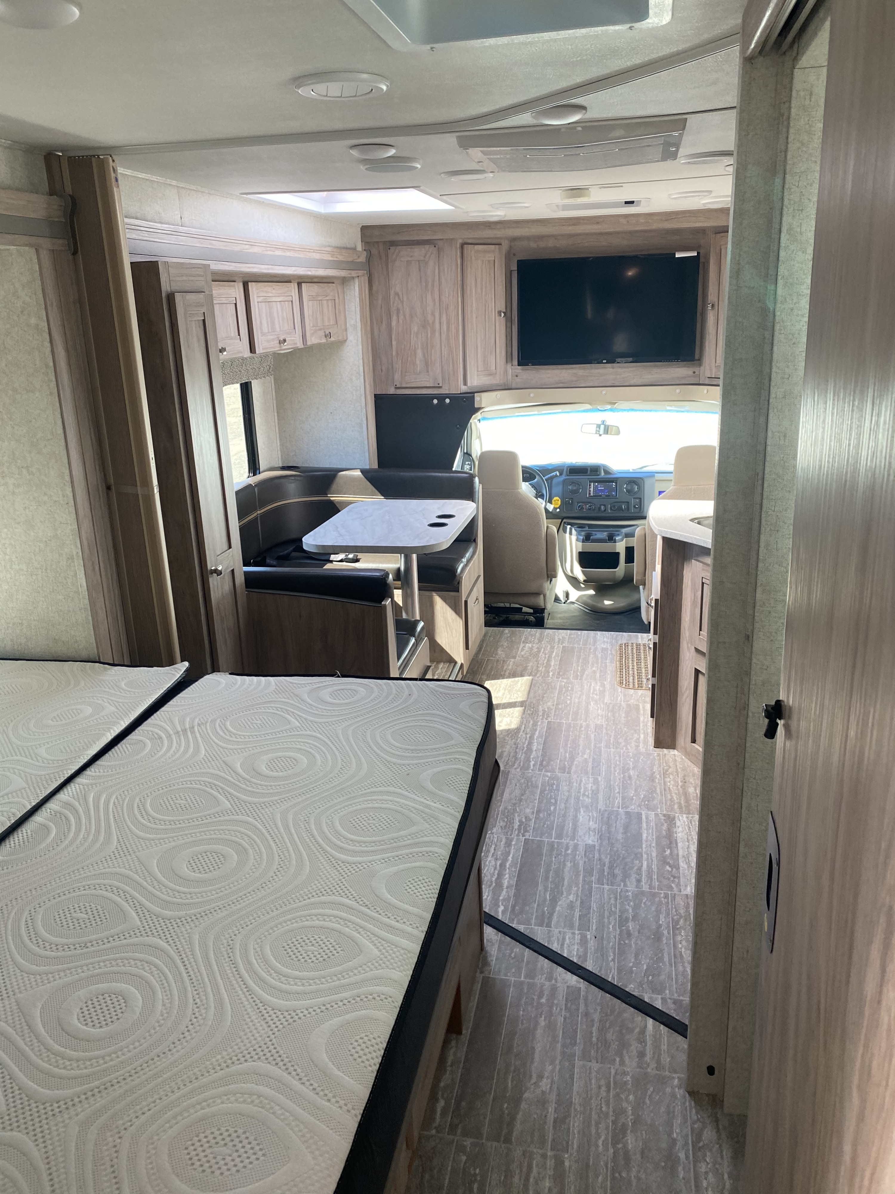 Step inside this RV rental. A view from the rear shows mattresses, a central dinette, and the driver's cockpit.. Ford E450 2013